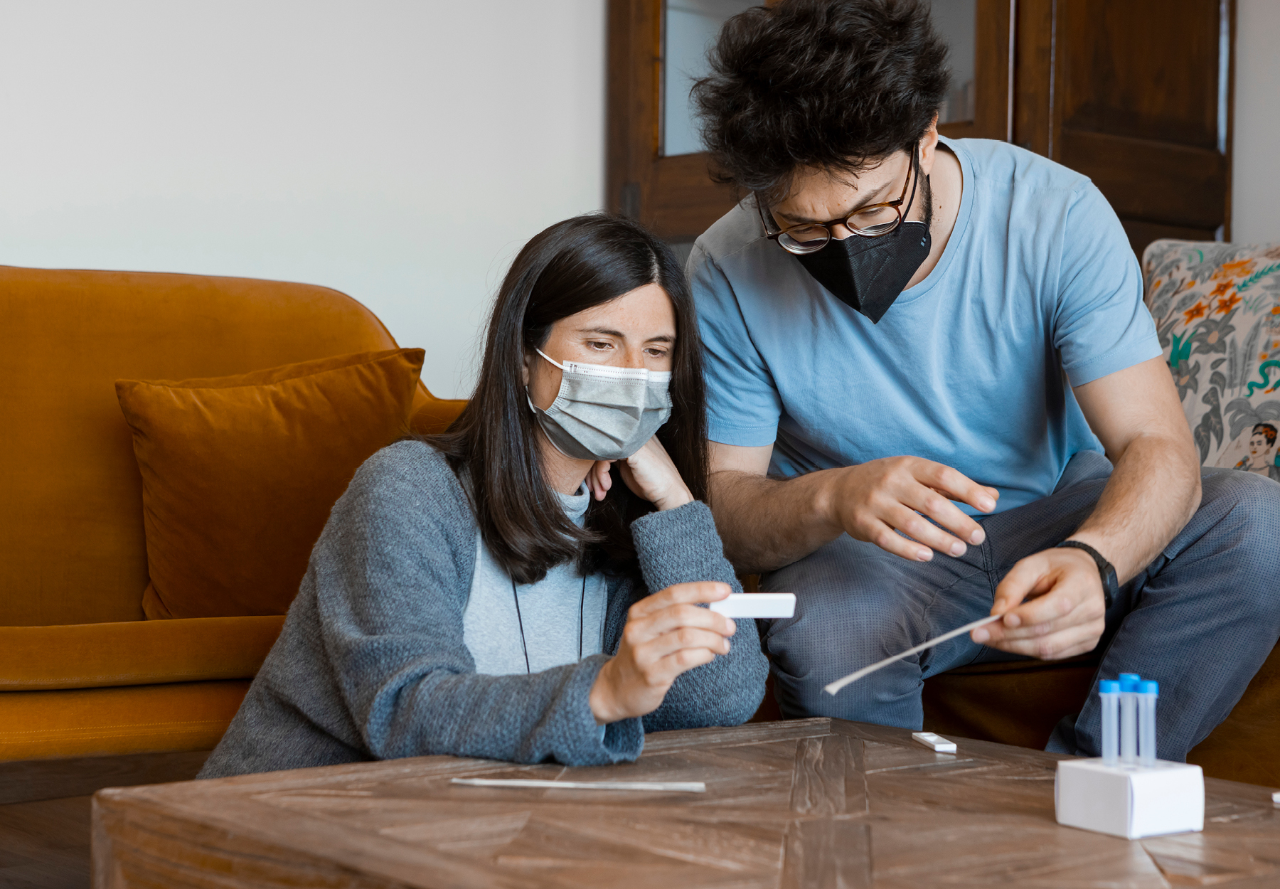 A man and woman examine the results of a COVID-19 rapid test in their living room.