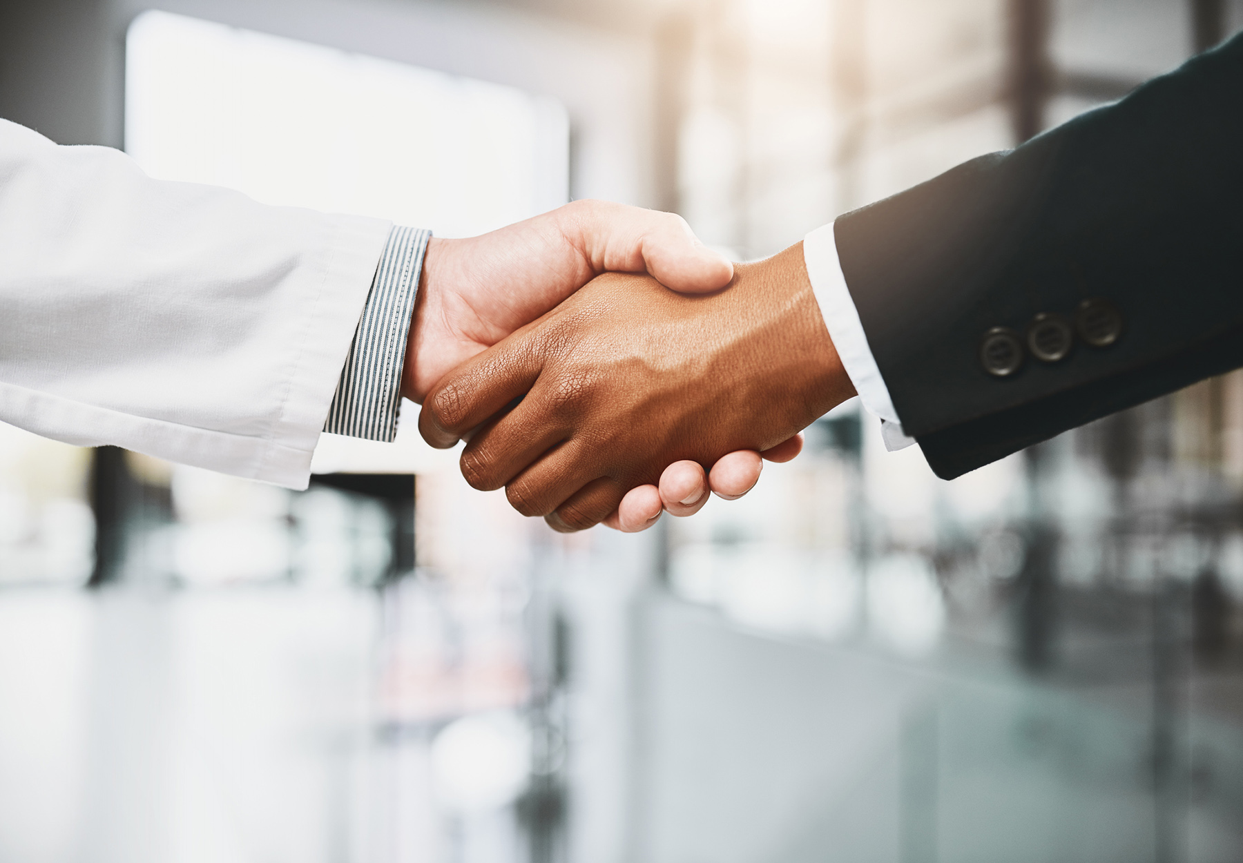 A closeup of a doctor shaking hands with a businessperson