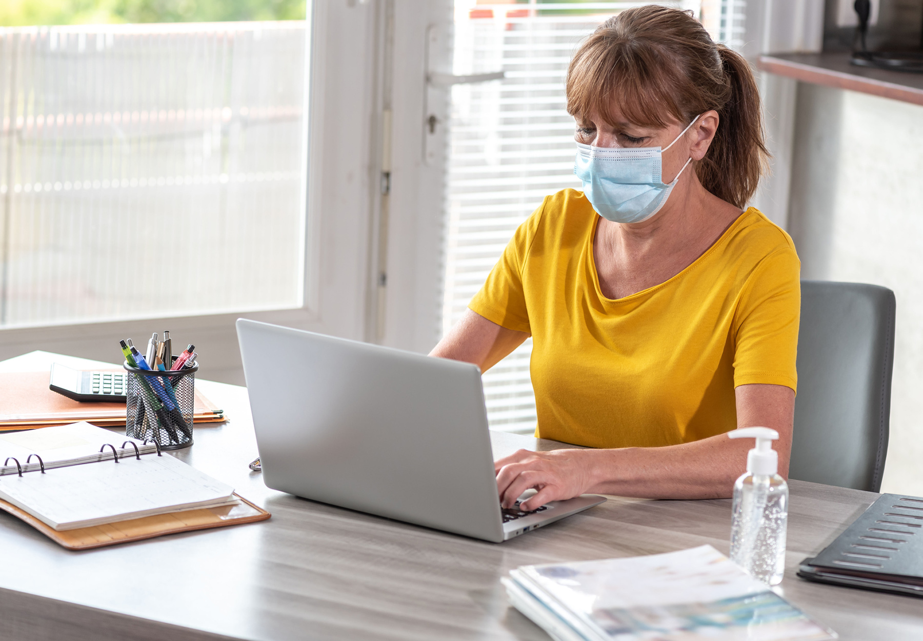 Woman wearing a face mask is ordering lab tests on her laptop.