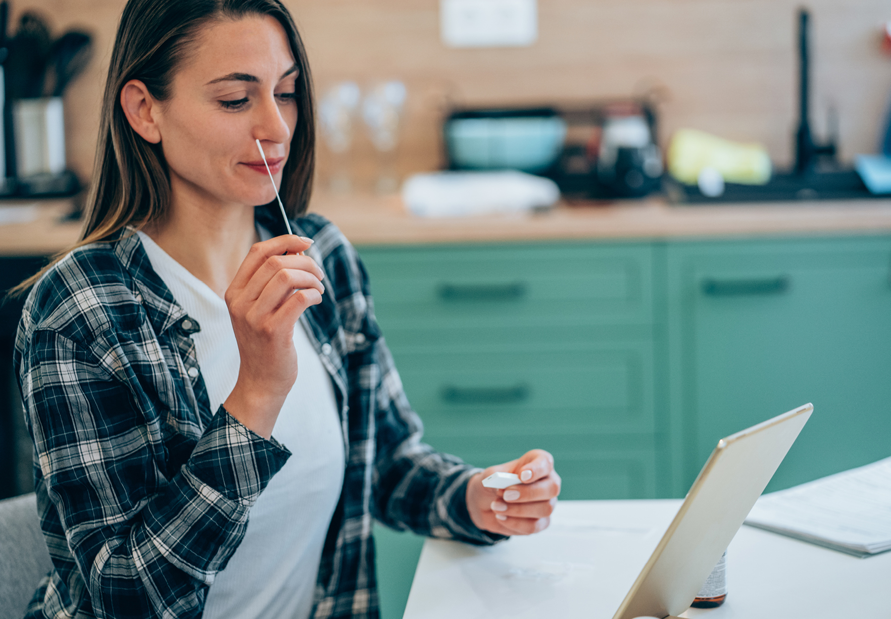 A woman swabbing her nose for an at-home SARS-CoV-2 test.