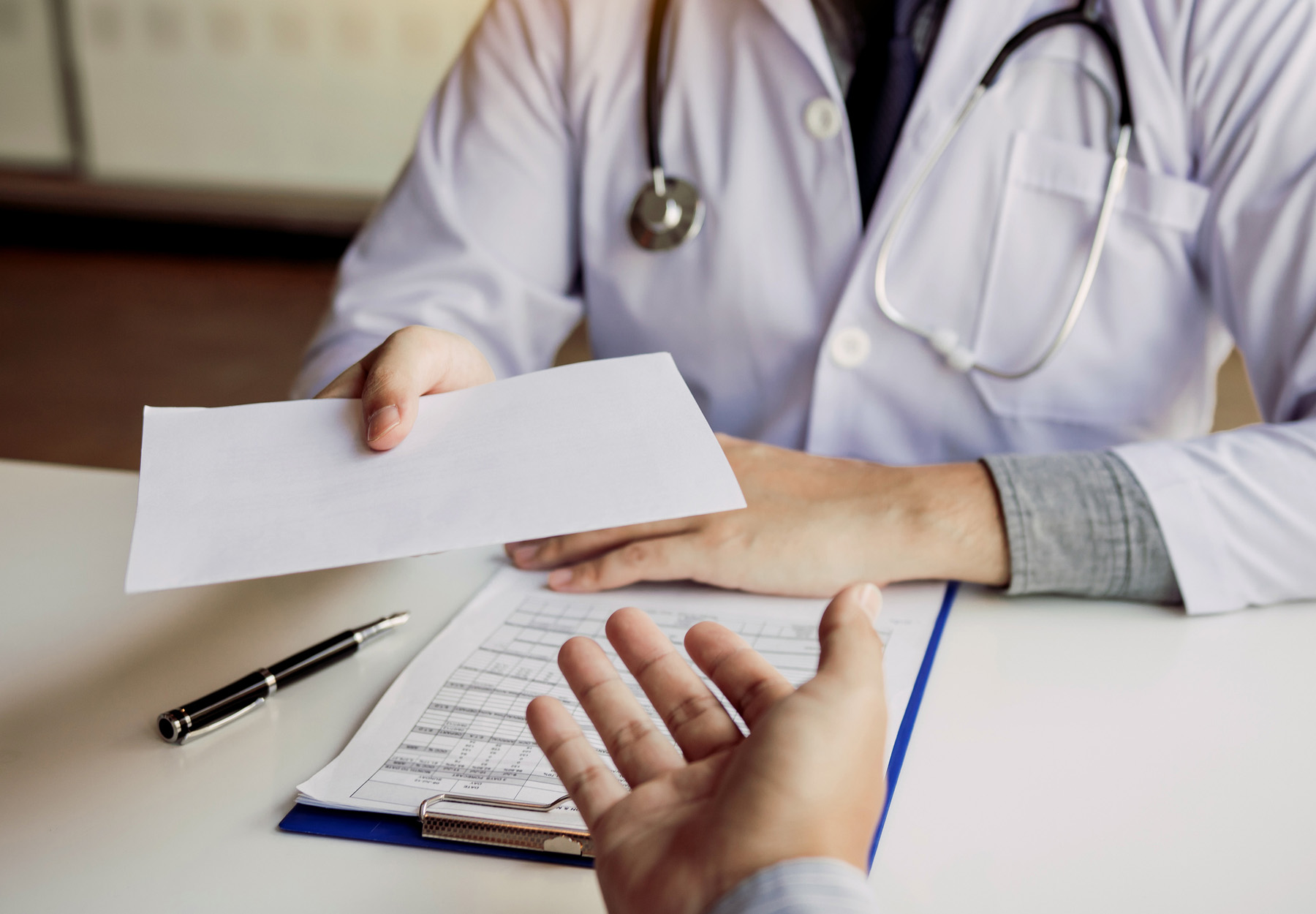 A doctor hands a document to a patient.