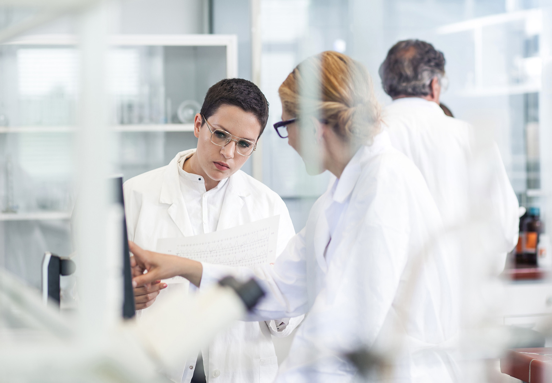 Laboratory staff examine something on a computer monitor in the laboratory.