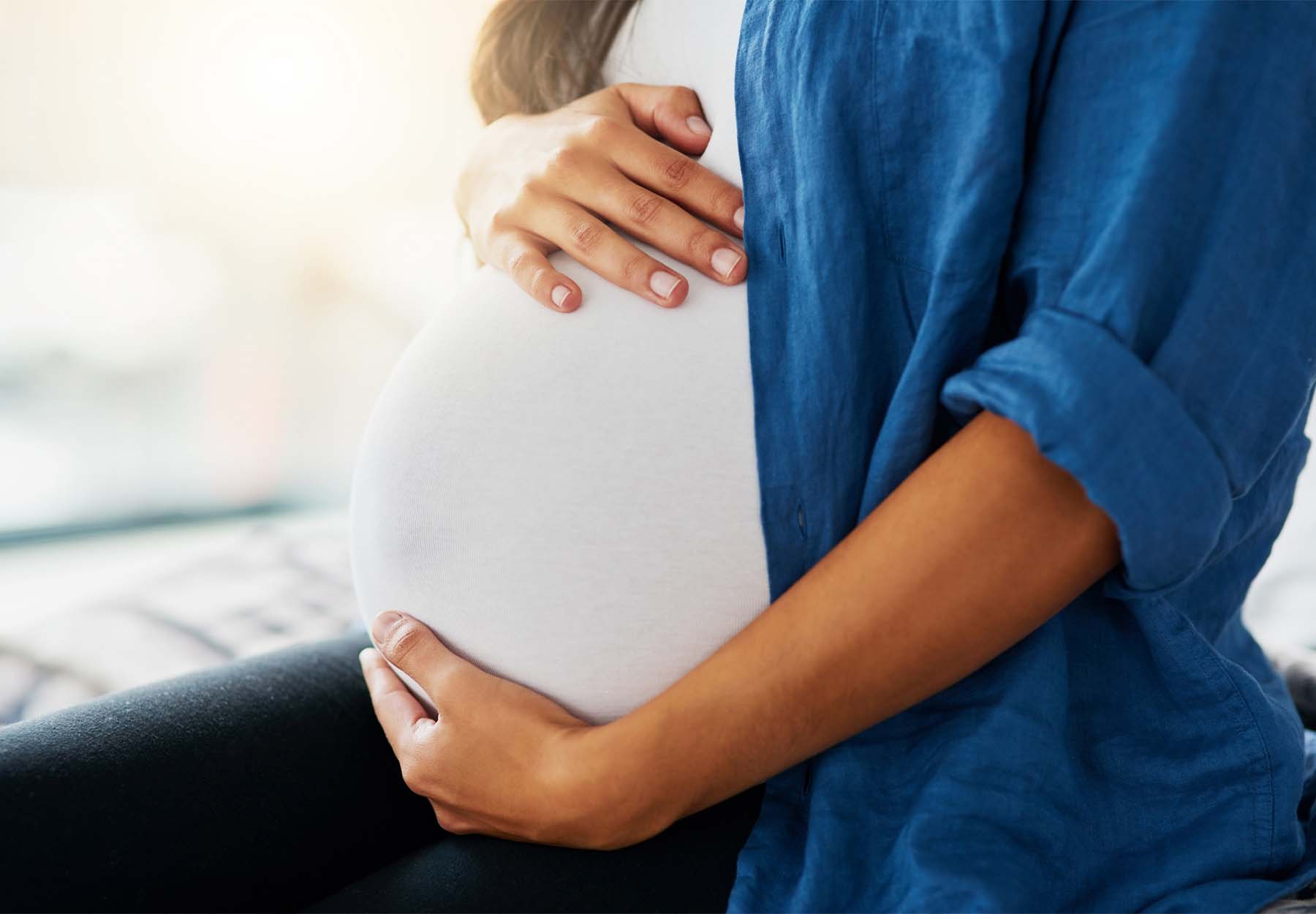 Closeup of pregnant woman holding her belly.