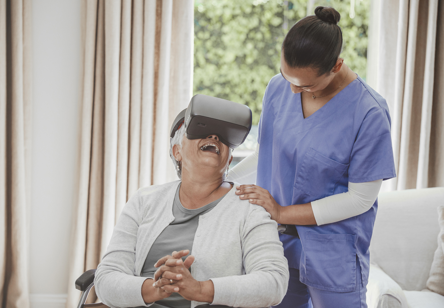 Old woman enjoying virtual reality simulator with her elder care nurse