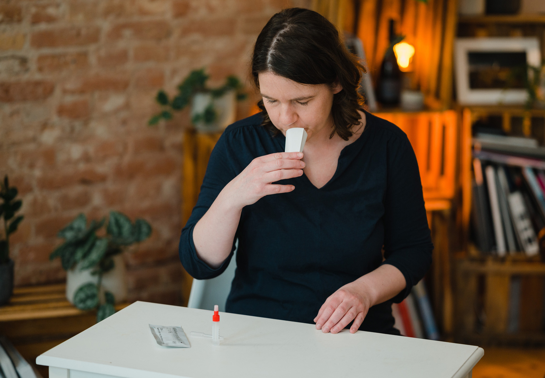 Woman spits into collection kit for at home COVID-19 test in this stock photo.