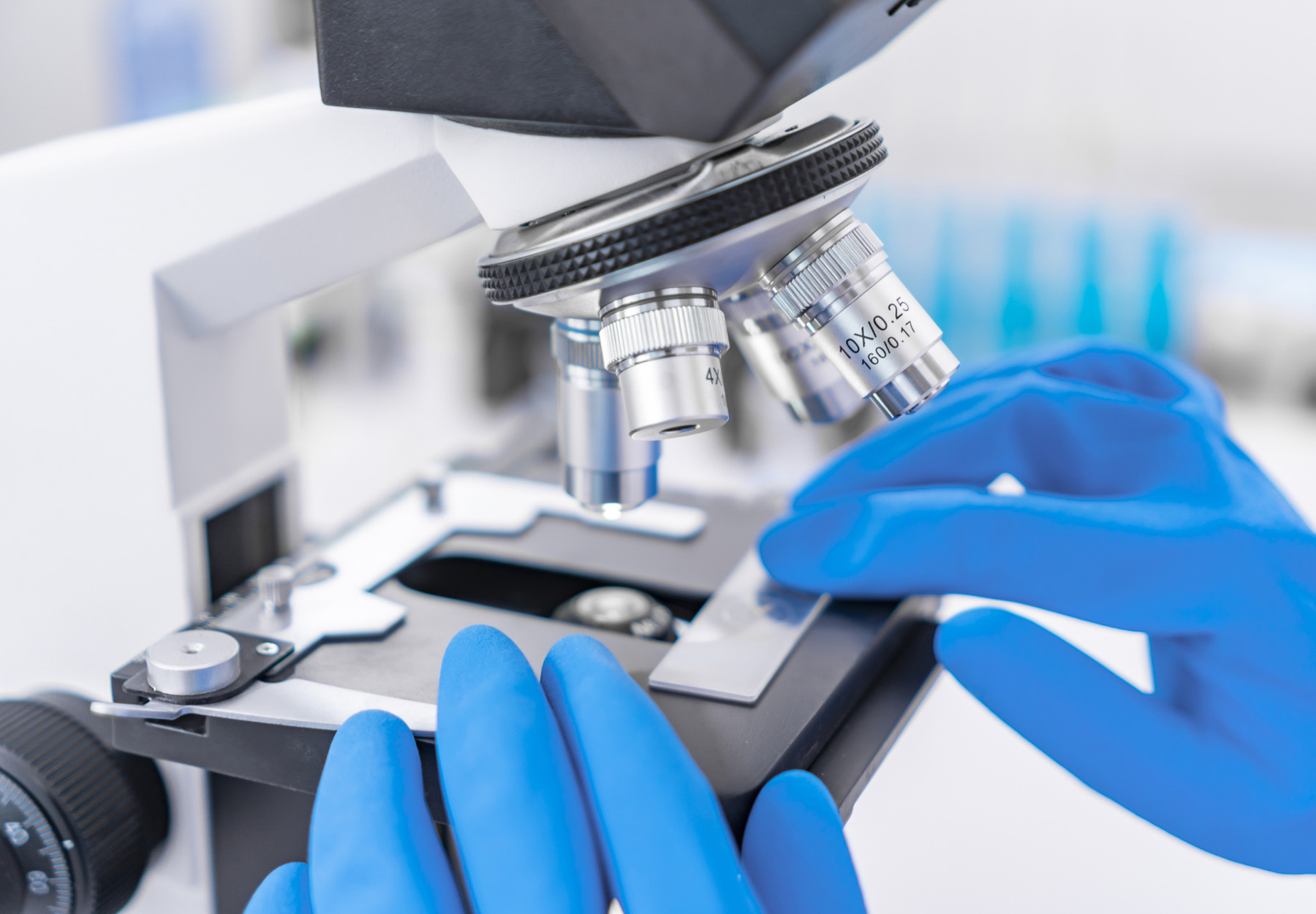 A closeup of a scientist putting a histology slide under a microscope