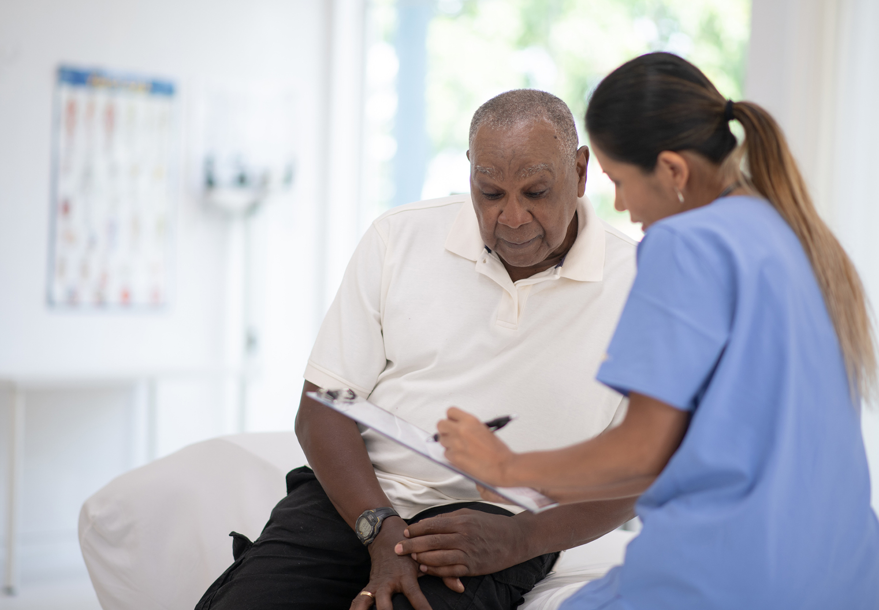 An African senior gentleman speaks with his doctor during a routine check-up in the doctor's office.