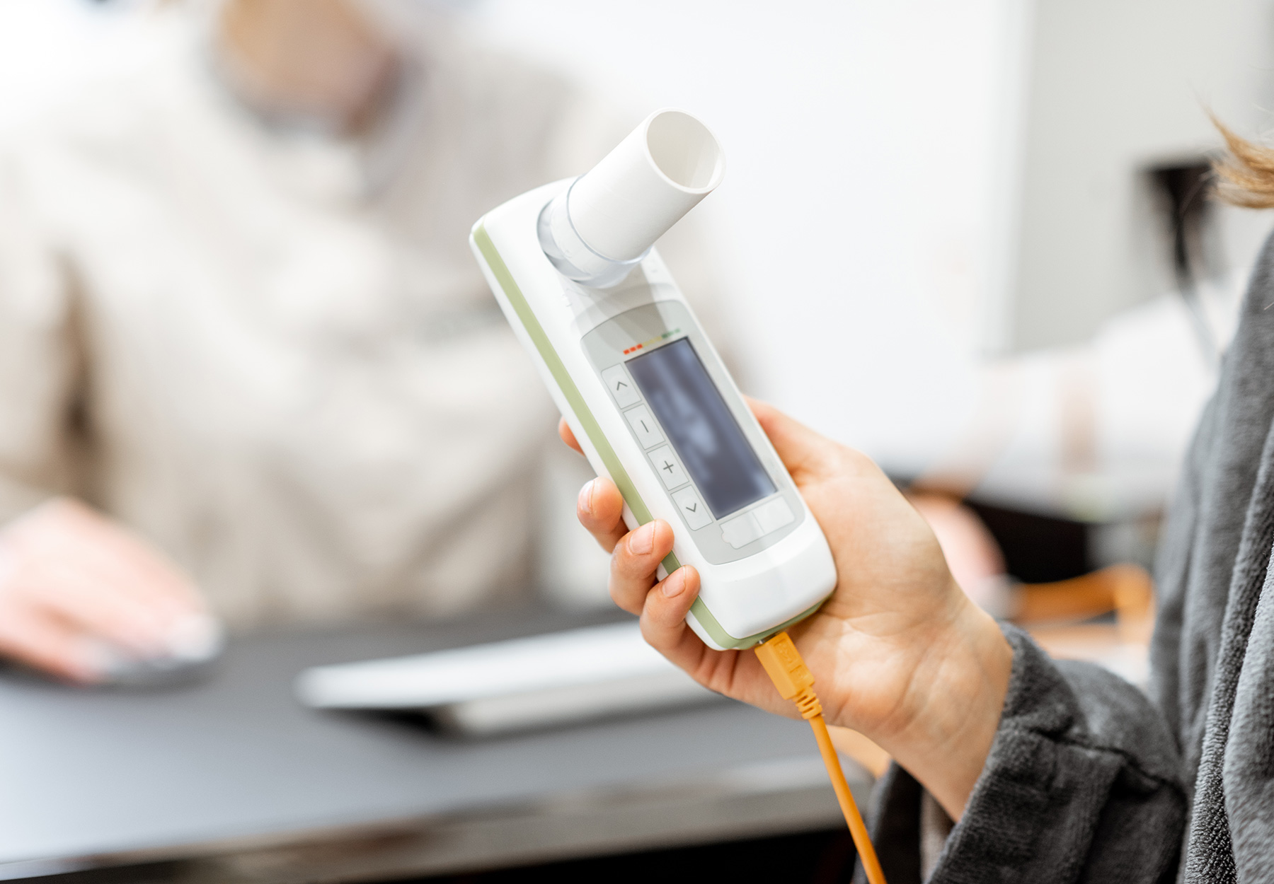 A closeup of a patient holding a spirometer device for measuring lung function.