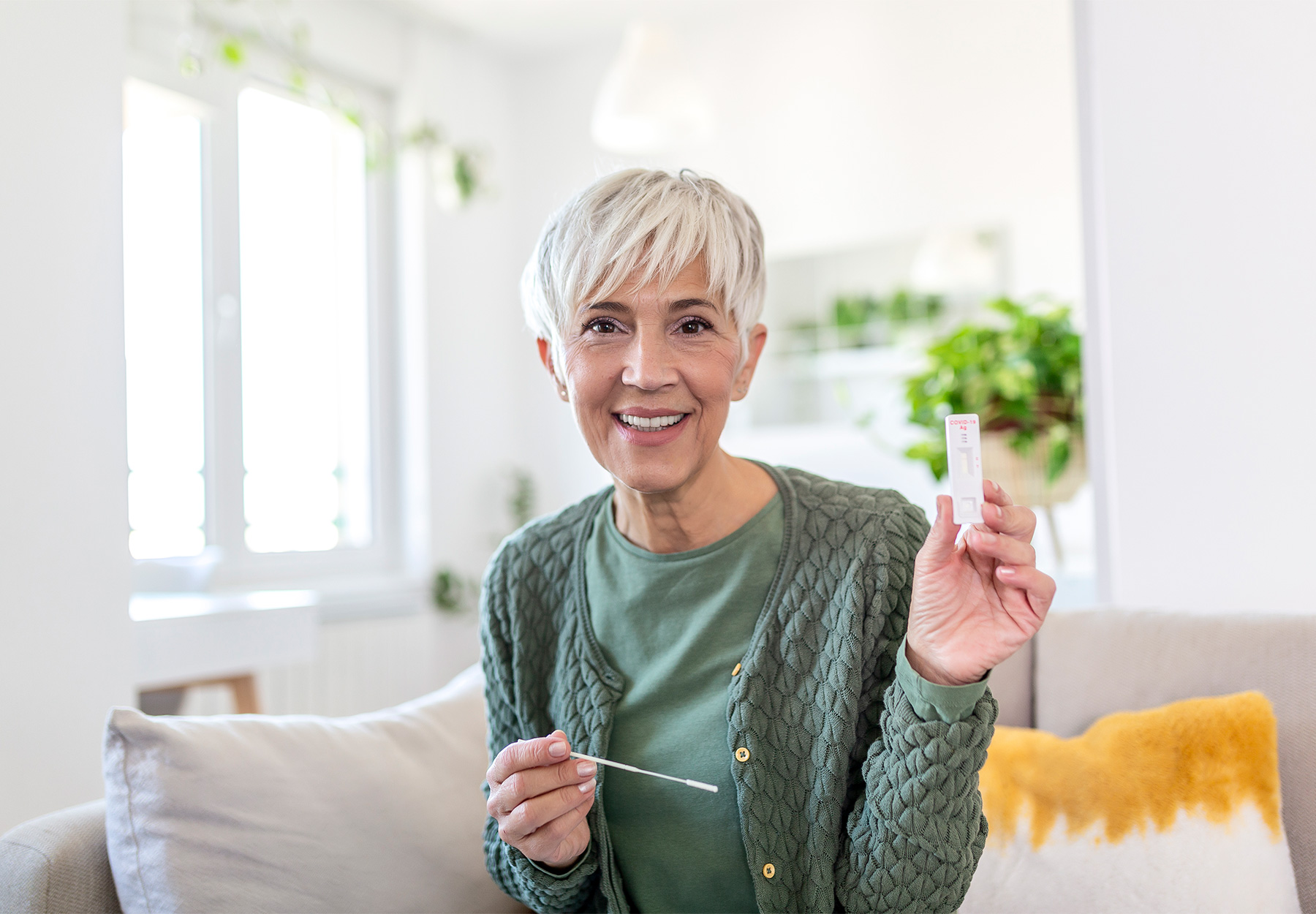 An elderly woman holds up a COVID-19 rapid test.