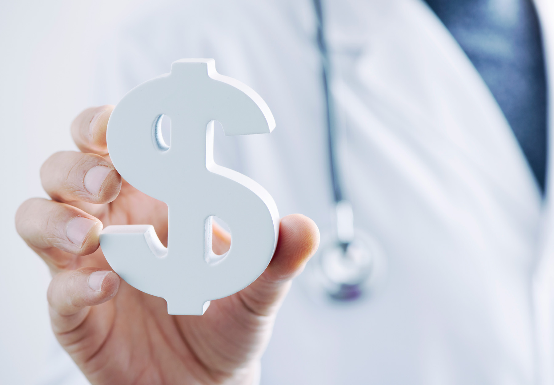 closeup of a young caucasian doctor with a dollar symbol in his hand, depicting settlement payments related to the health care industry