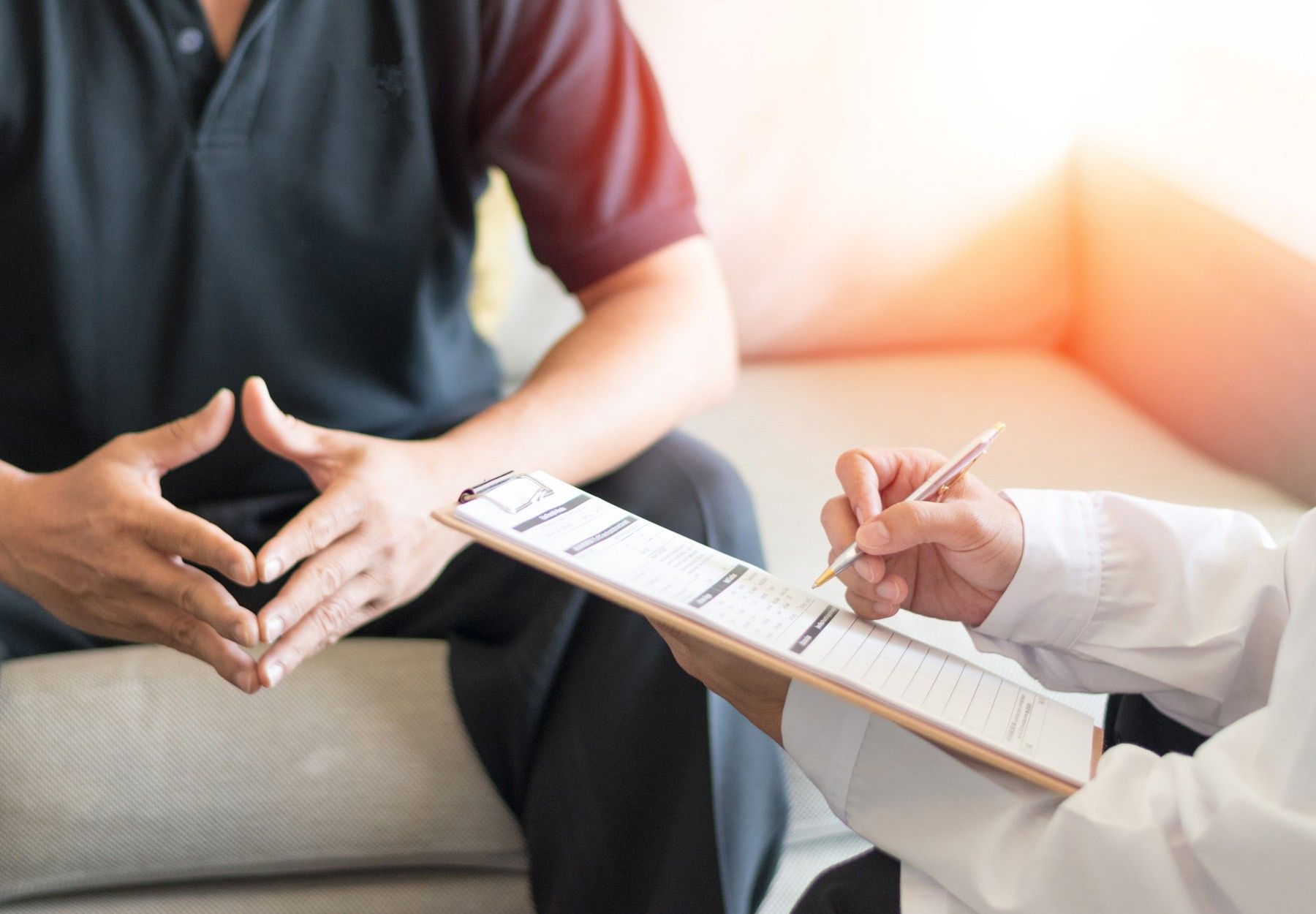 a closeup of a man meeting with his doctor. The doctor is holding a clipboard.