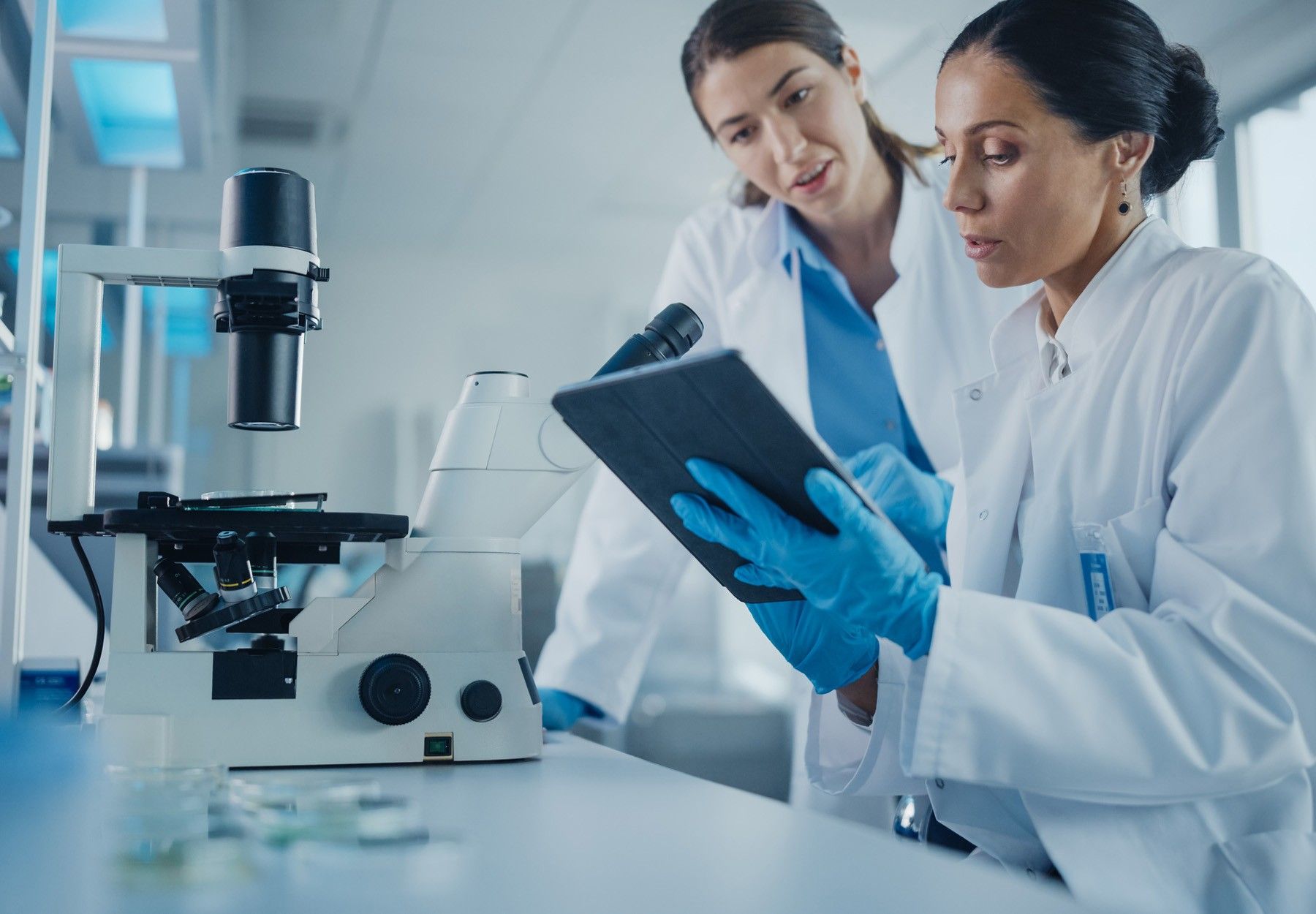 A stock photo of two female lab employees consulting in the lab while looking at a tablet