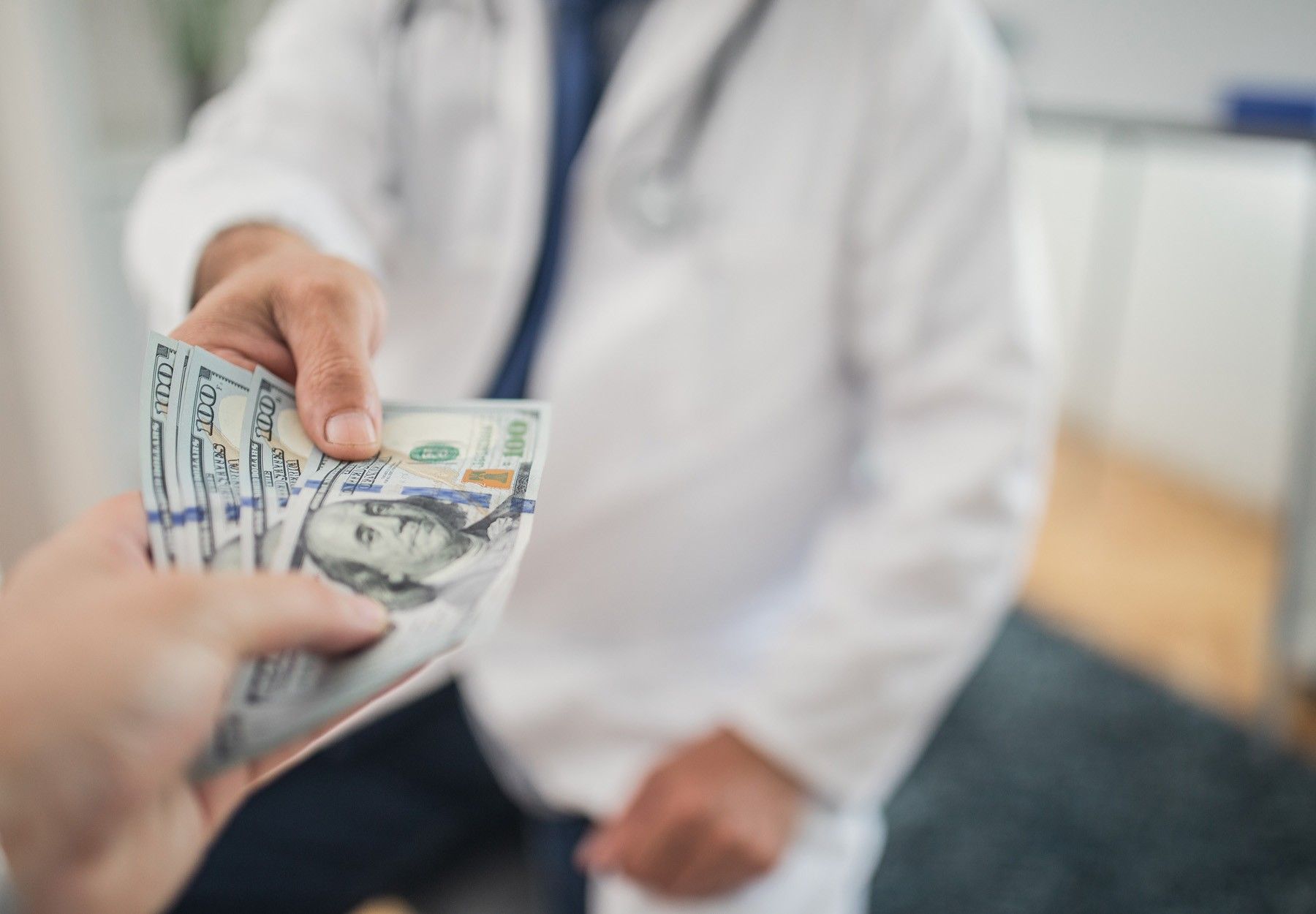 A closeup of someone giving money to a physician as a bribe stock photo