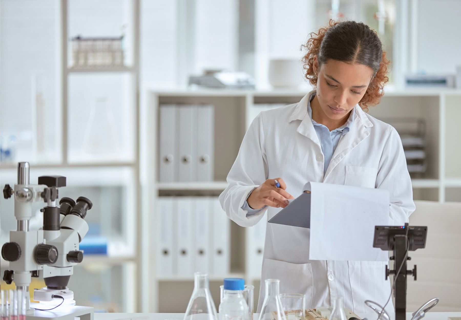 A female lab employee looks at a clipboard in the lab