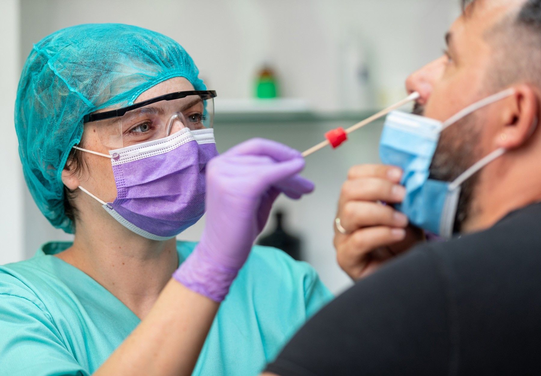 Female health care worker collecting a nasopharyngeal swab sample from a male patient