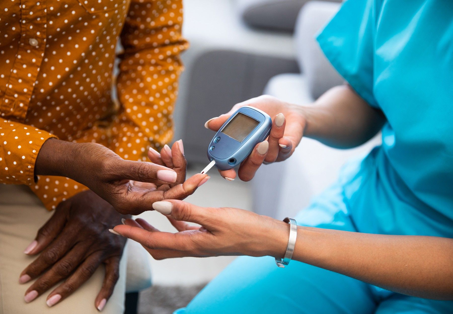 Closeup of nurse doing a blood glucose test on a Black patient