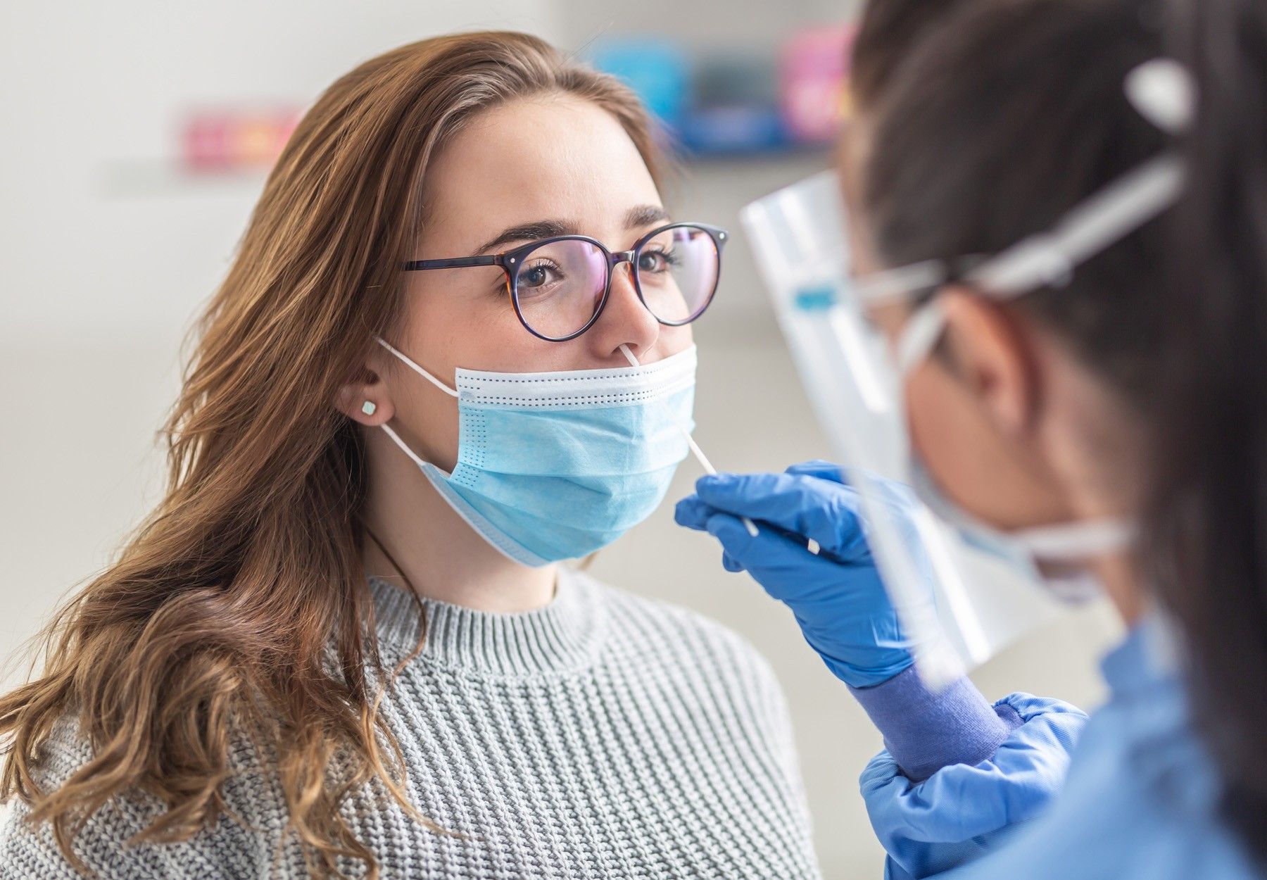 Woman getting a nasal swab from a health care worker for a COVID-19 test