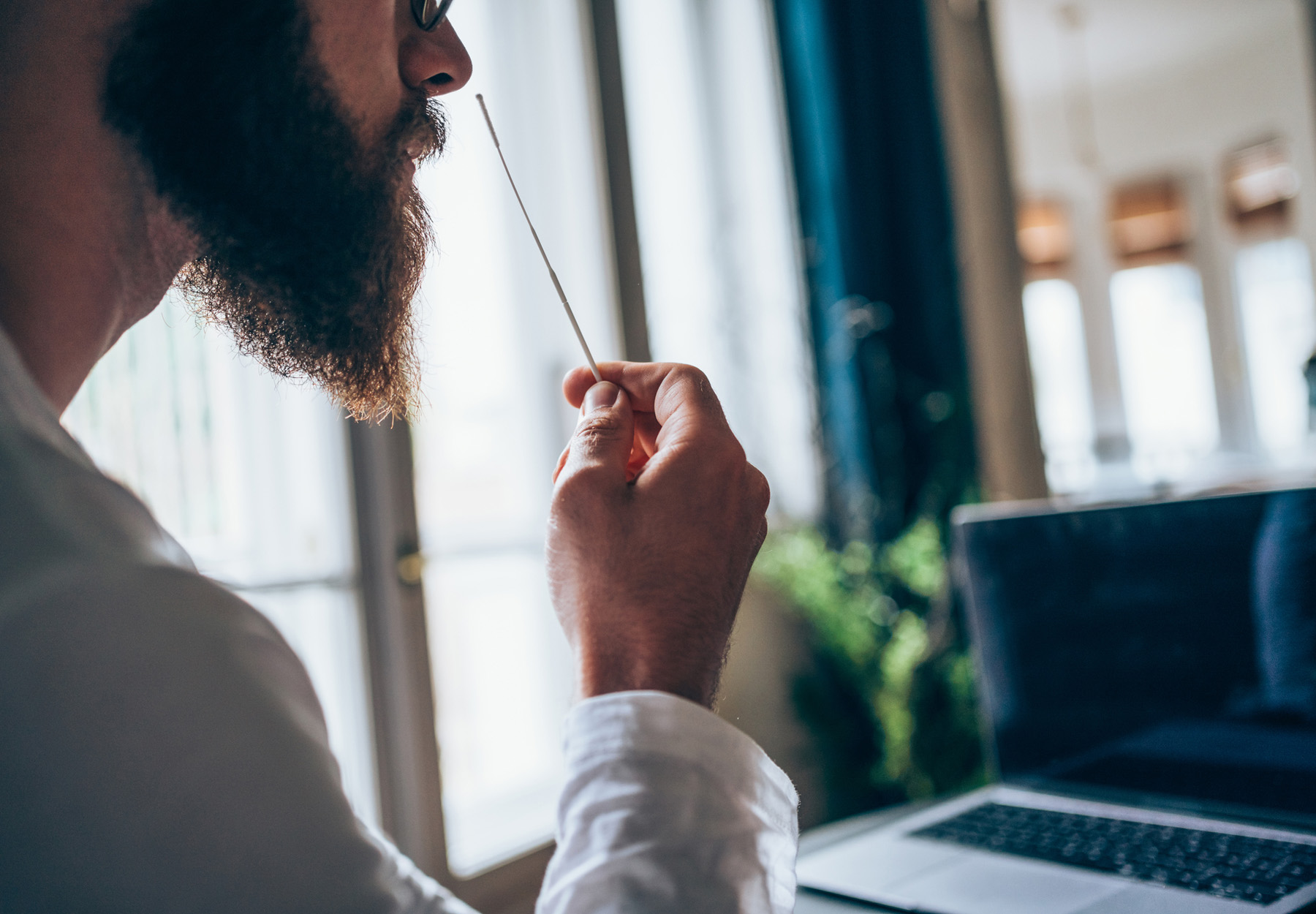 Shot of a man using cotton swab while doing coronavirus PCR test at home.