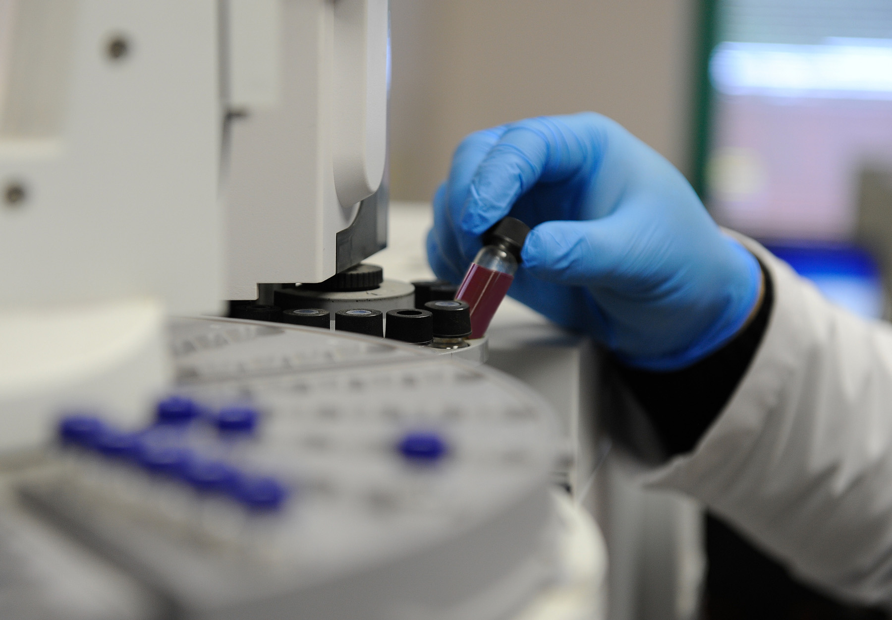 A closeup of a lab worker loading a blood sample into a machine for testing stock image