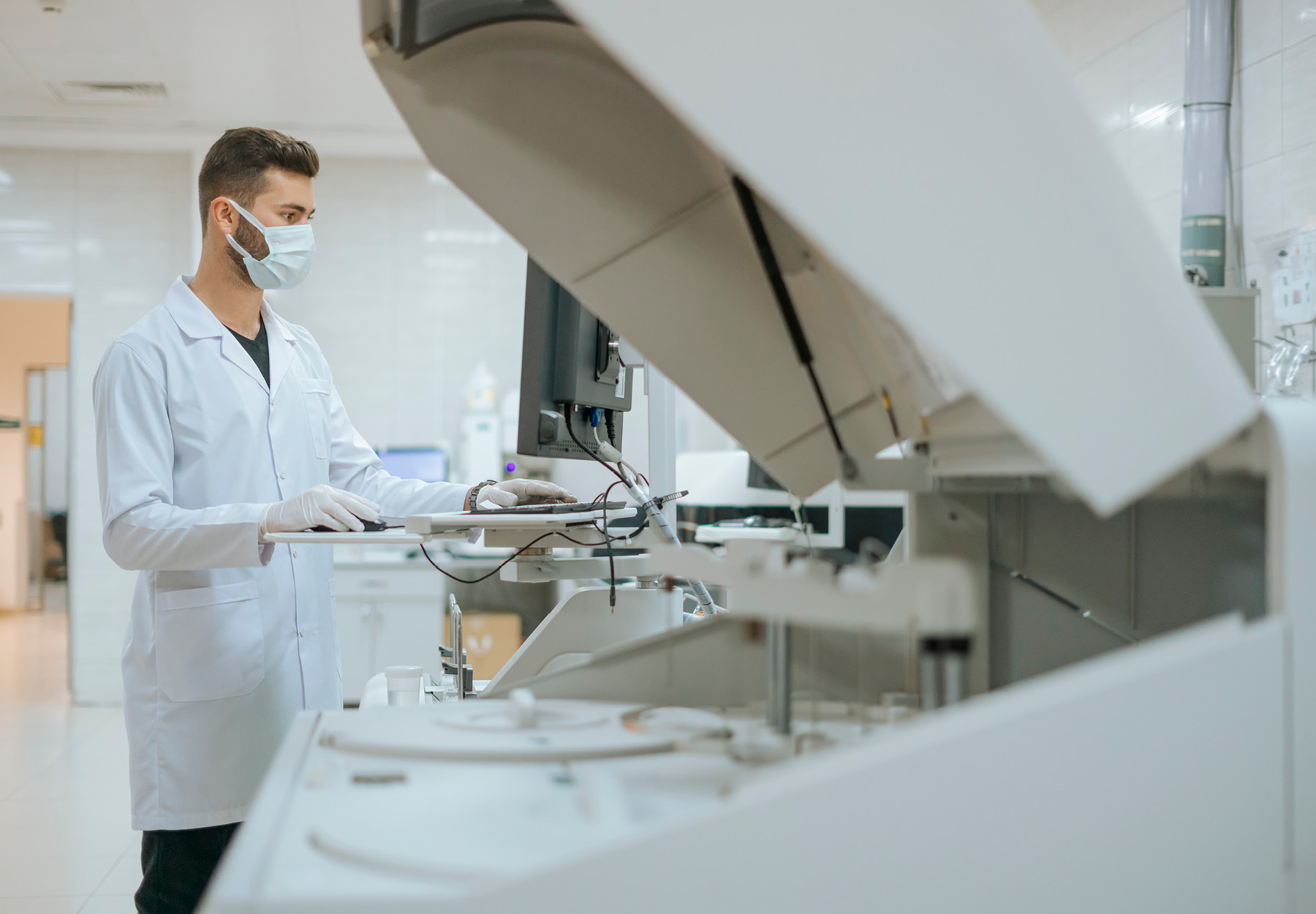 A male lab technician operates a machine in the lab.