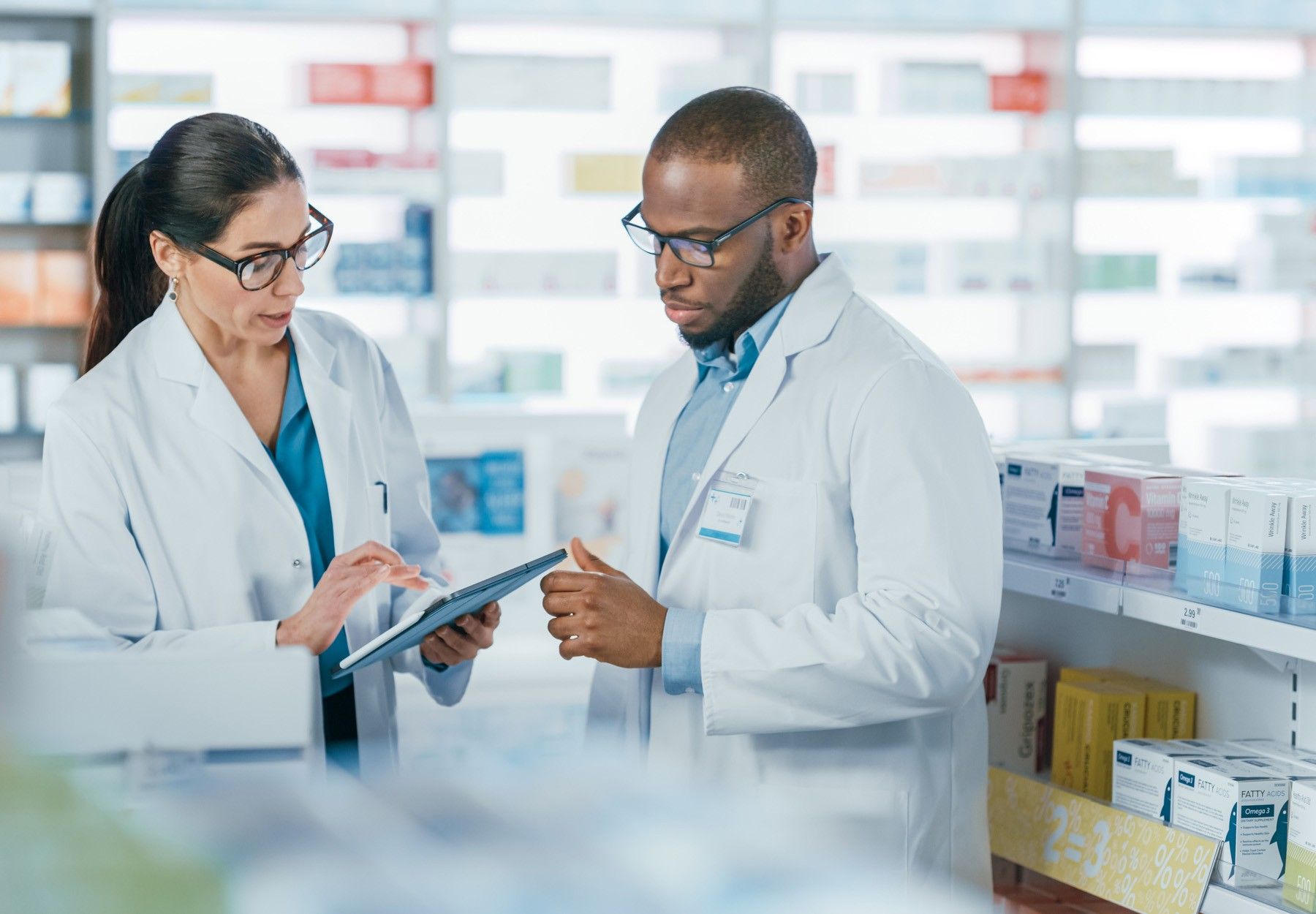 Stock image of two staff members in a pharmacy discussing something