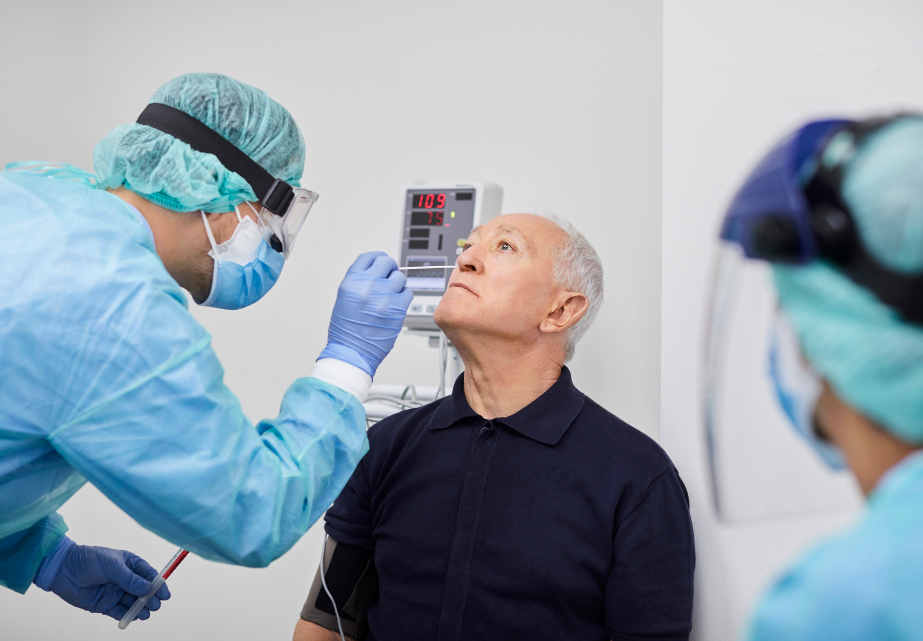 a health care worker does a nasal swab on an elderly man for a COVID-19 test stock photo