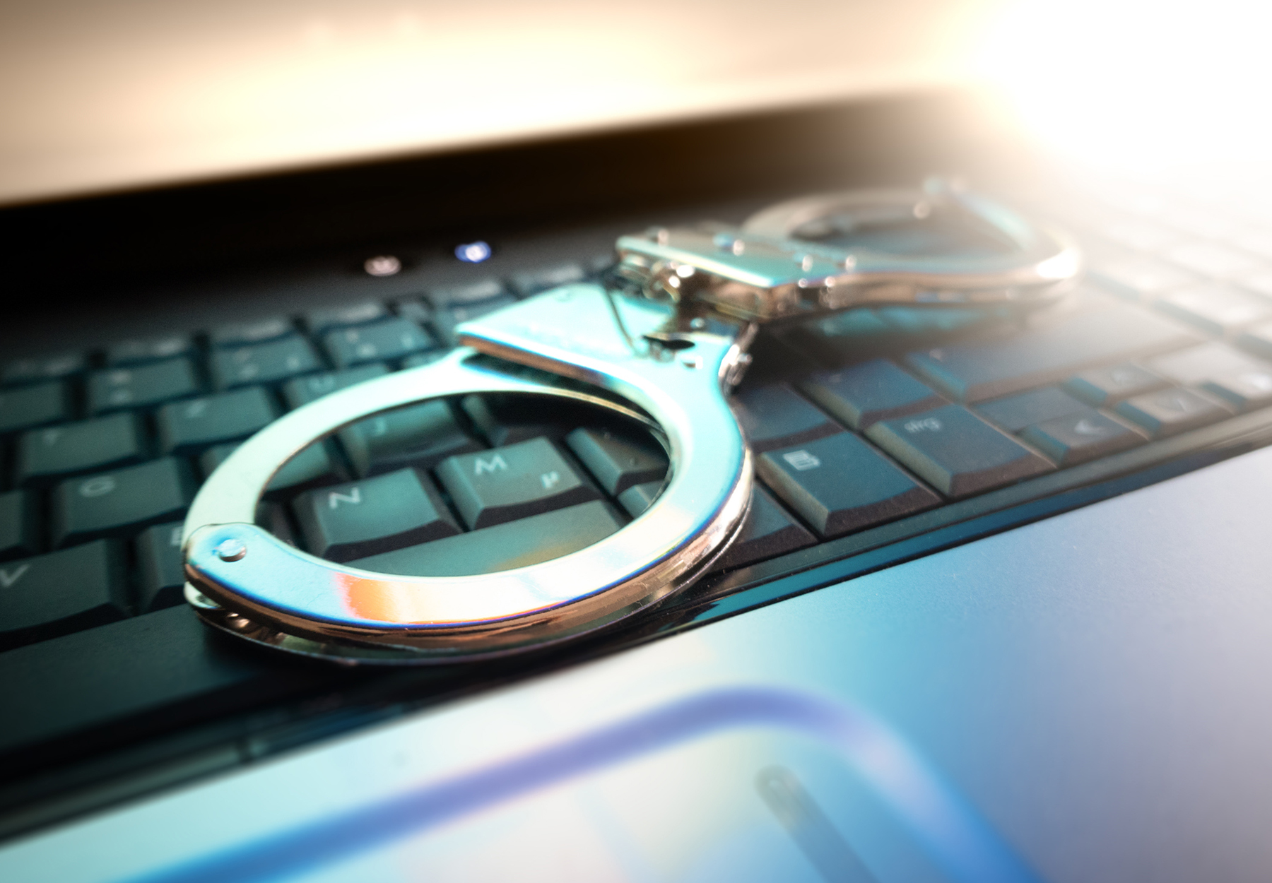 Stock image of handcuffs on computer keyboard to symbolize telemedicine fraud