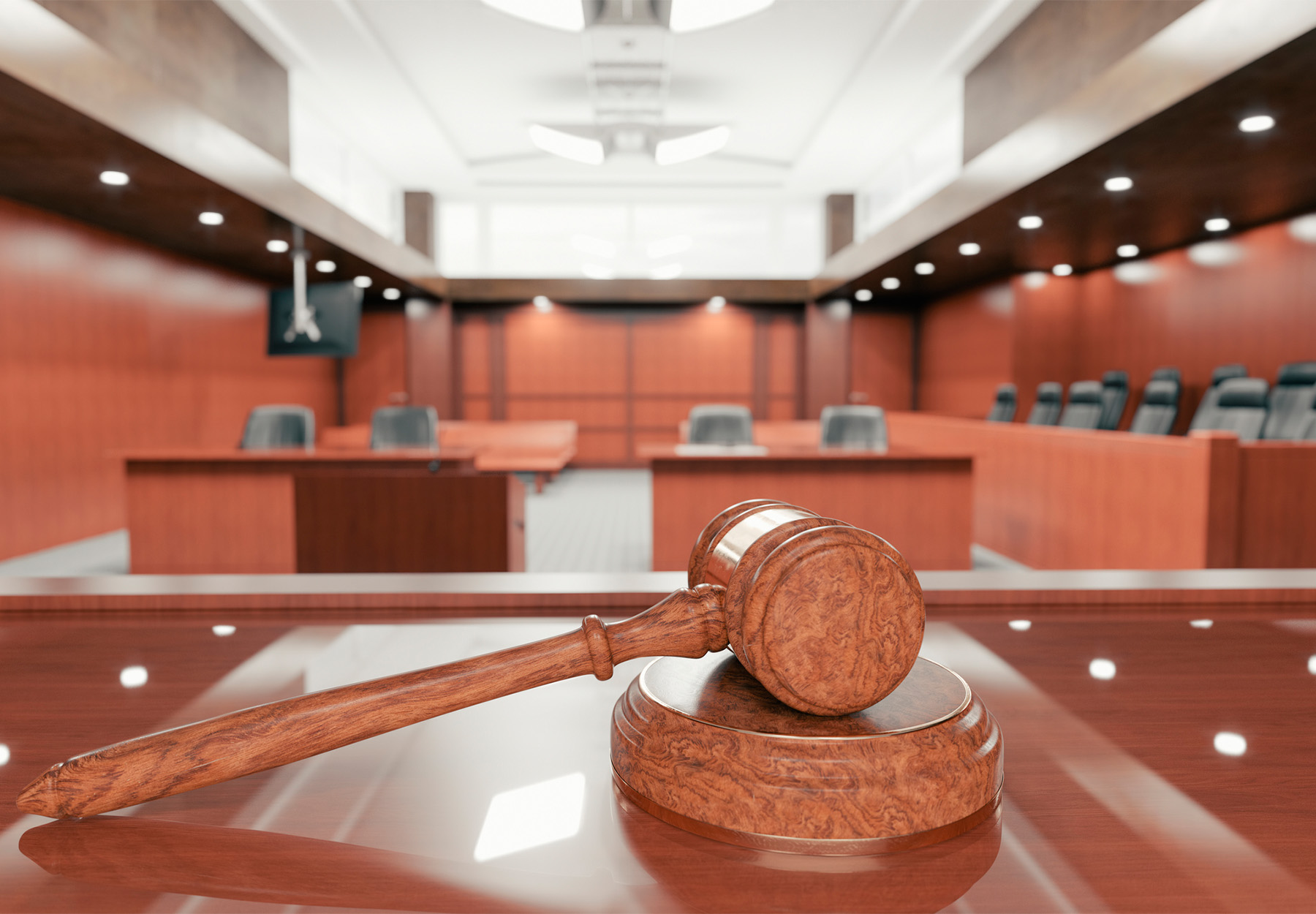 Stock image of the interior of an empty courtroom with gavel and sounding block on the desk