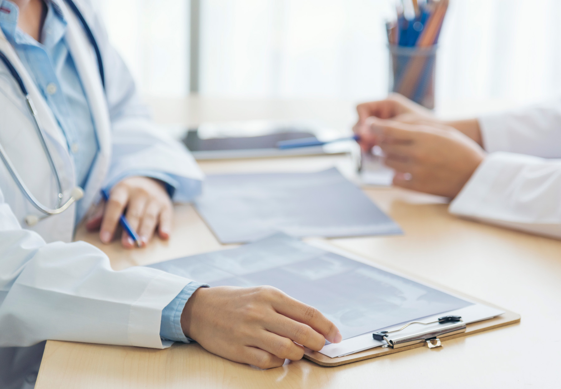 Doctor and lab worker filling out paperwork at a desk stock image