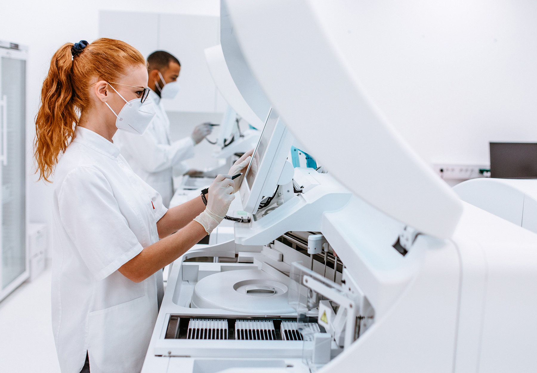 Laboratory professionals operating large, automated equipment in the lab. Stock image.