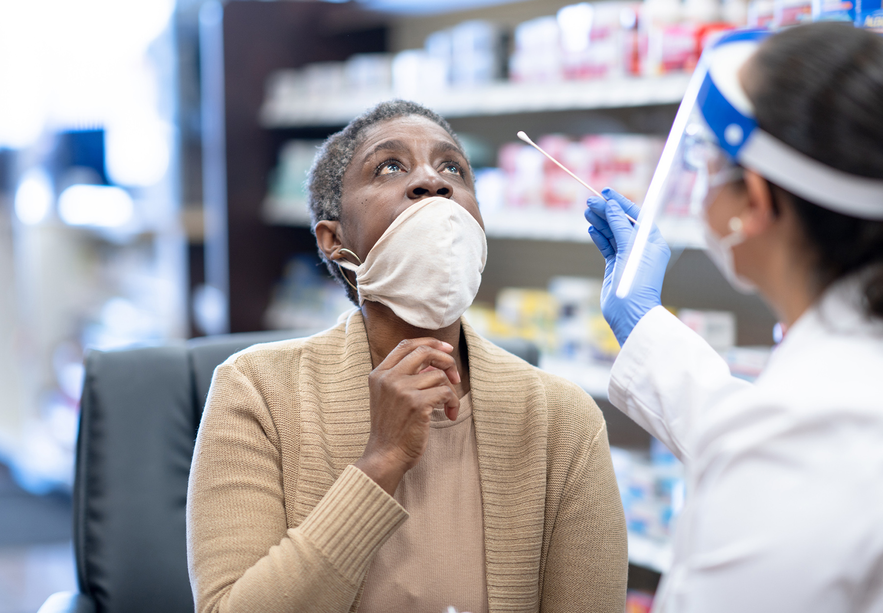 Senior African American female getting nasal swab from a healthcare professional for a COVID-19 test. Stock photo.