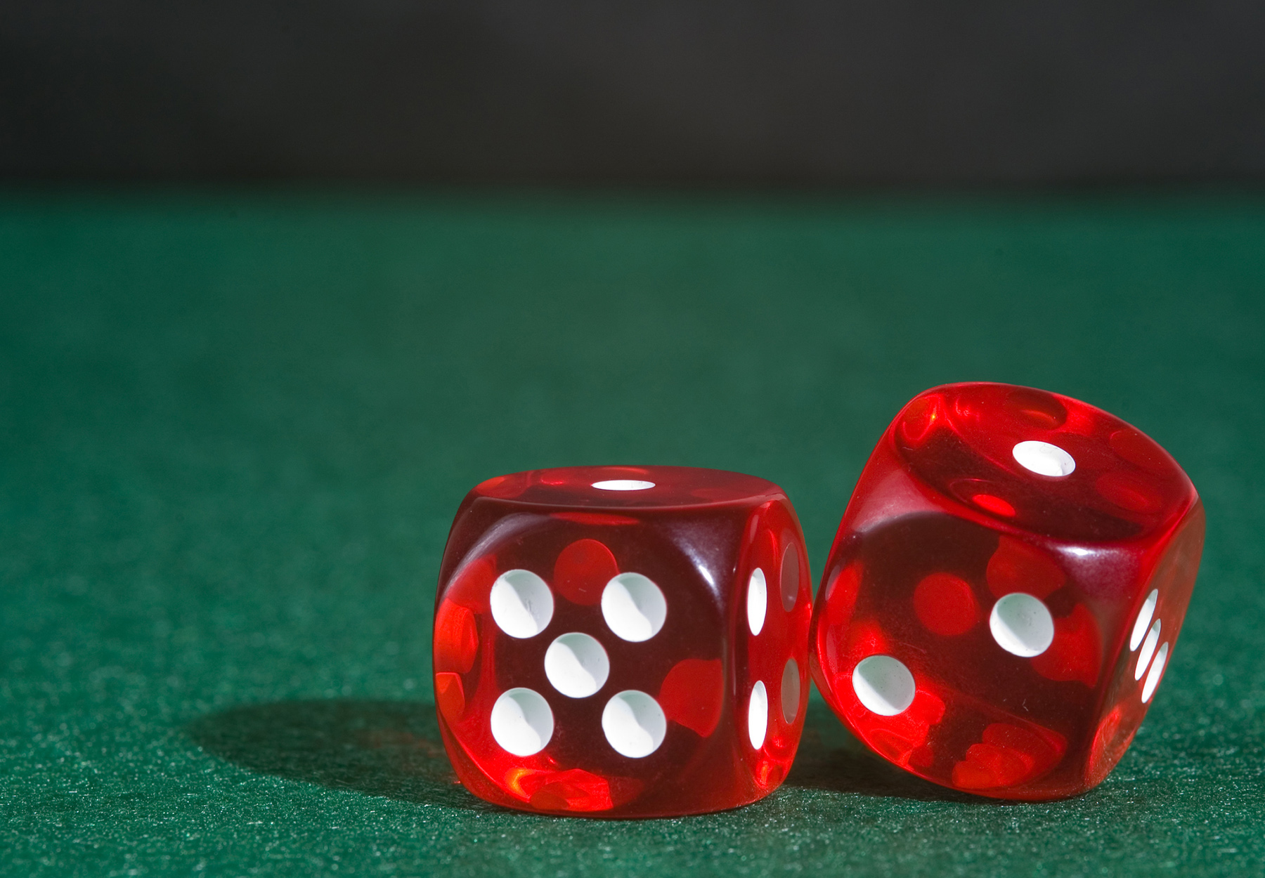 Red Las Vegas Casino-style dice on green felt, showing snake eyes. Stock photo.