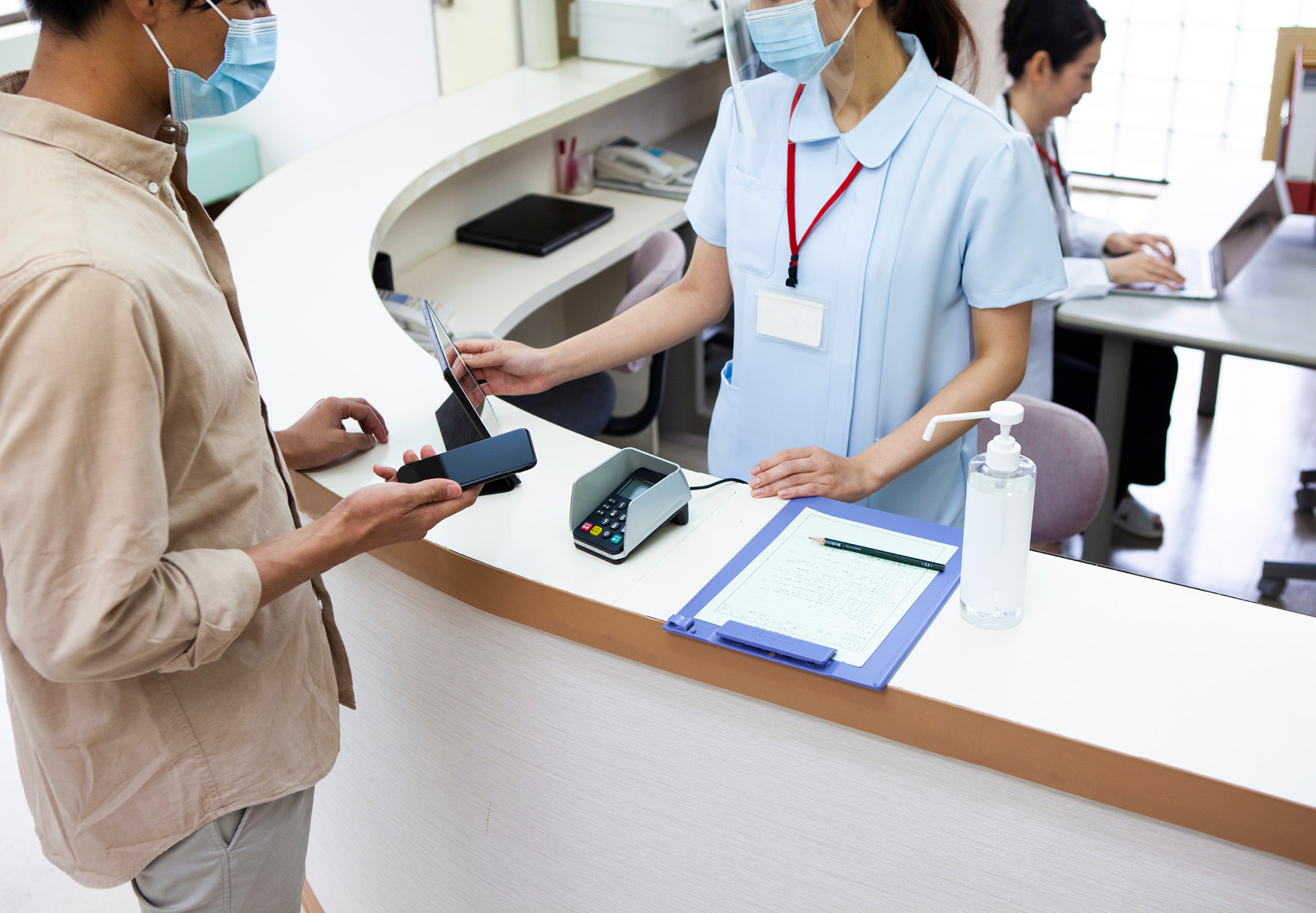 Man paying his bills at the front desk of a hospital