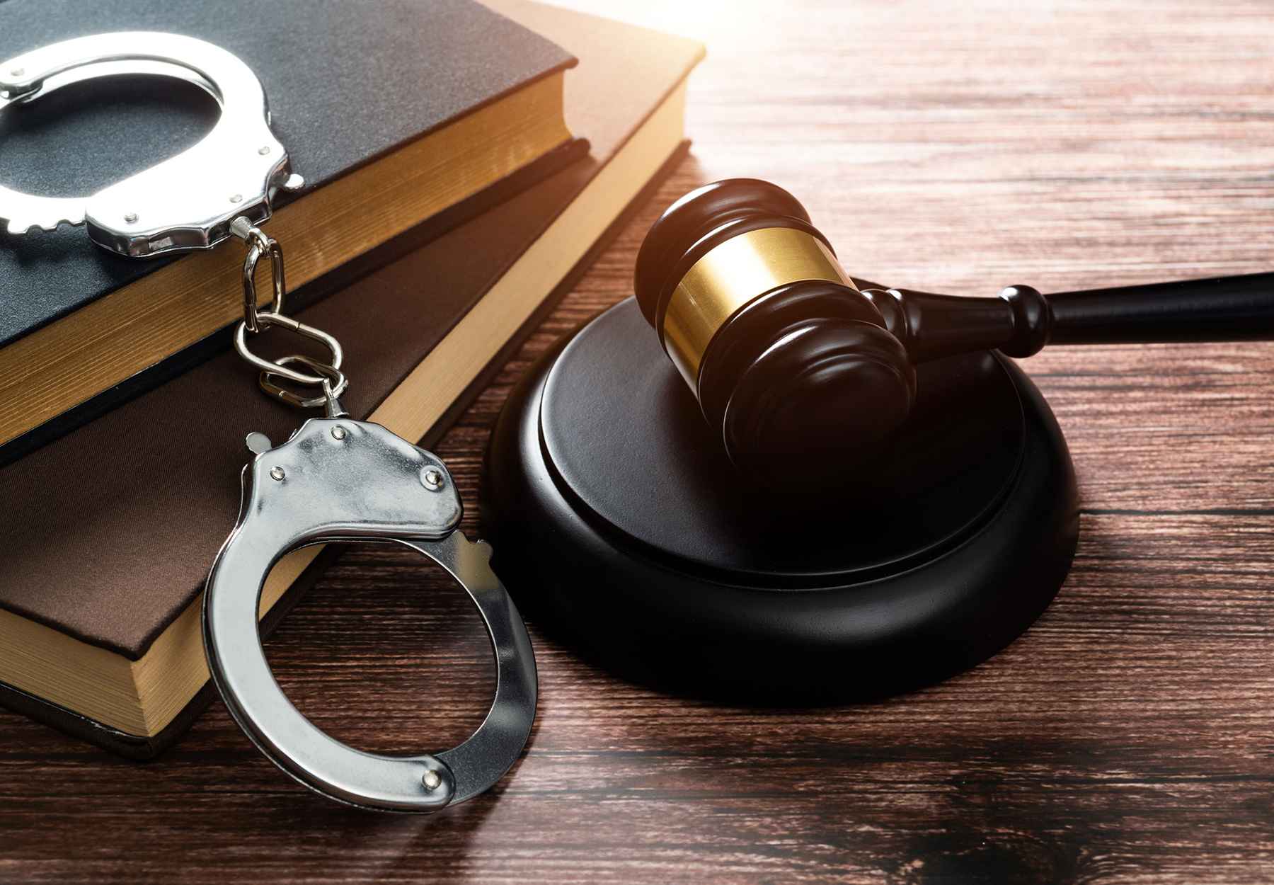 stock image of gavel, handcuffs, and book on wooden table to show concept of guilty verdict