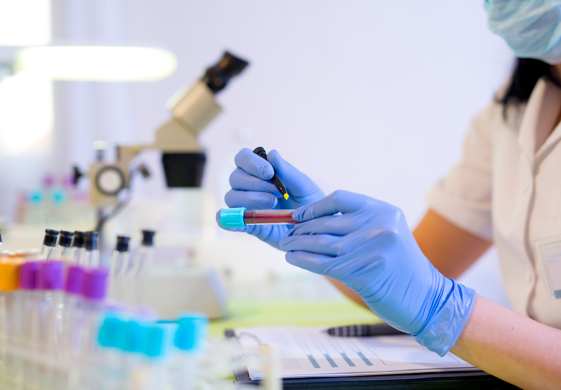 Lab worker writing on a blood sample tube in the lab.