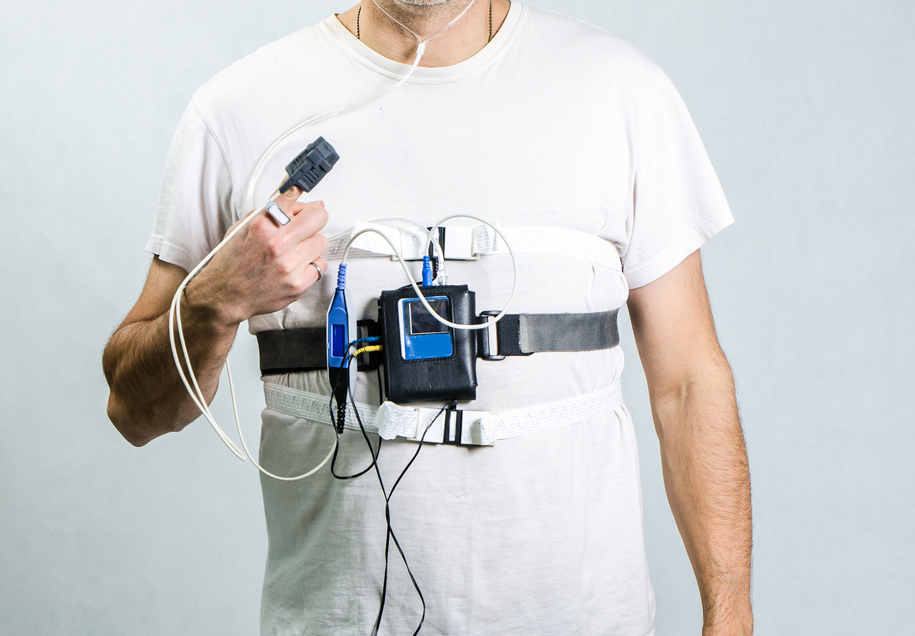 Closeup photo of man in white T-shirt who is also wearing sleep apnea monitoring equipment. Stock photo.