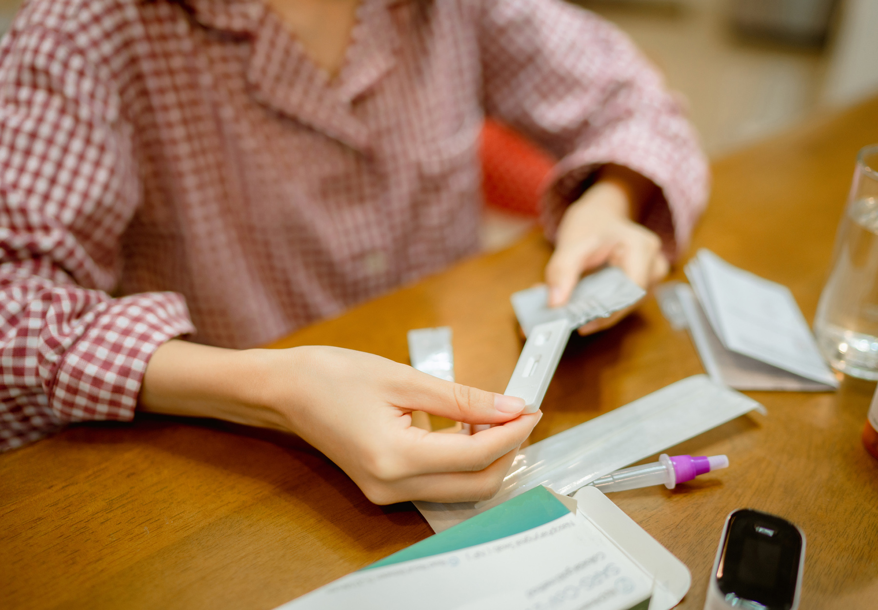 Woman unpacking and reading how to use COVID-19 antigen test kit during quarantine at home. Stock image.