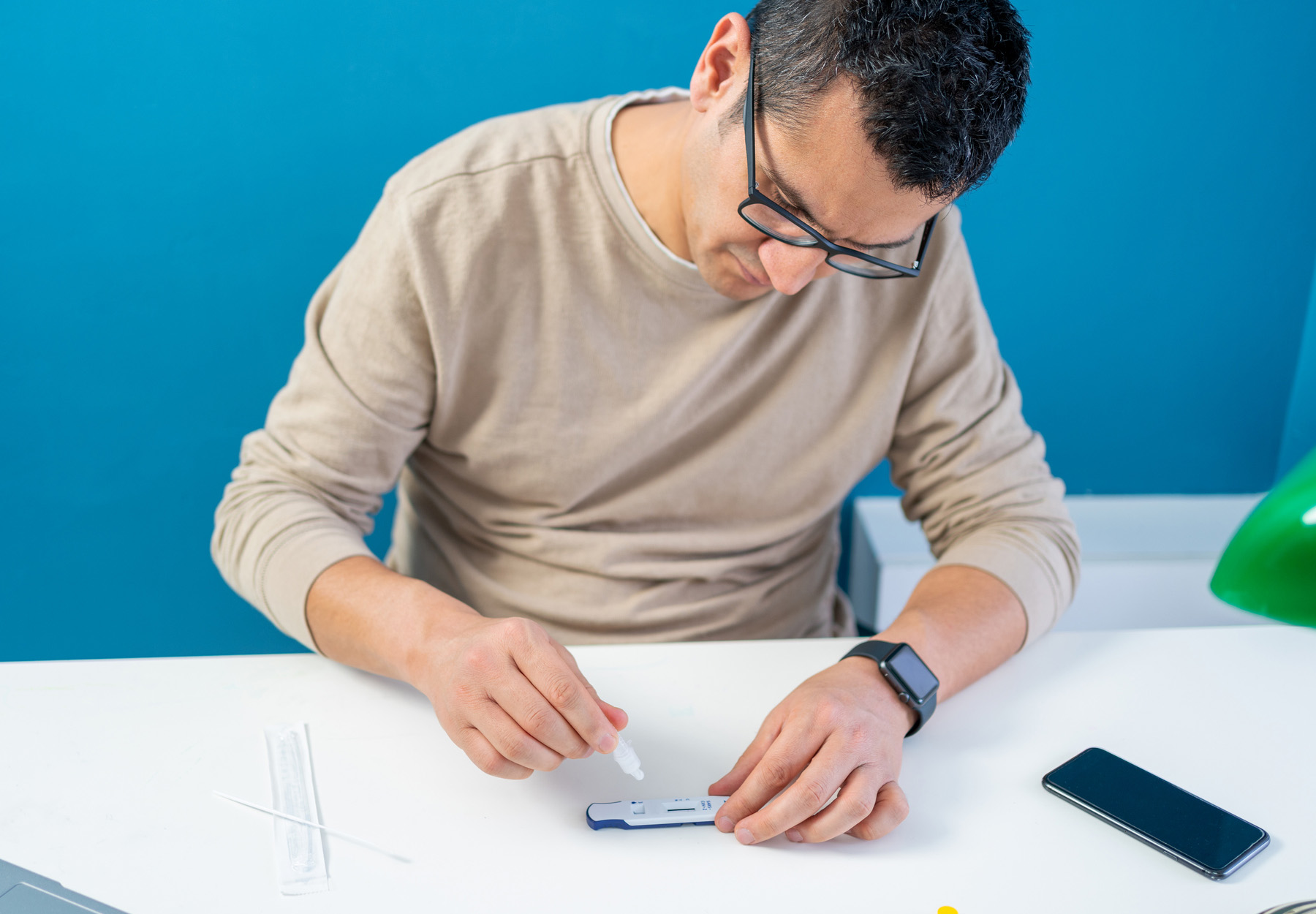 Man doing an at-home rapid antigen test for COVID-19 in his home office. Stock photo.