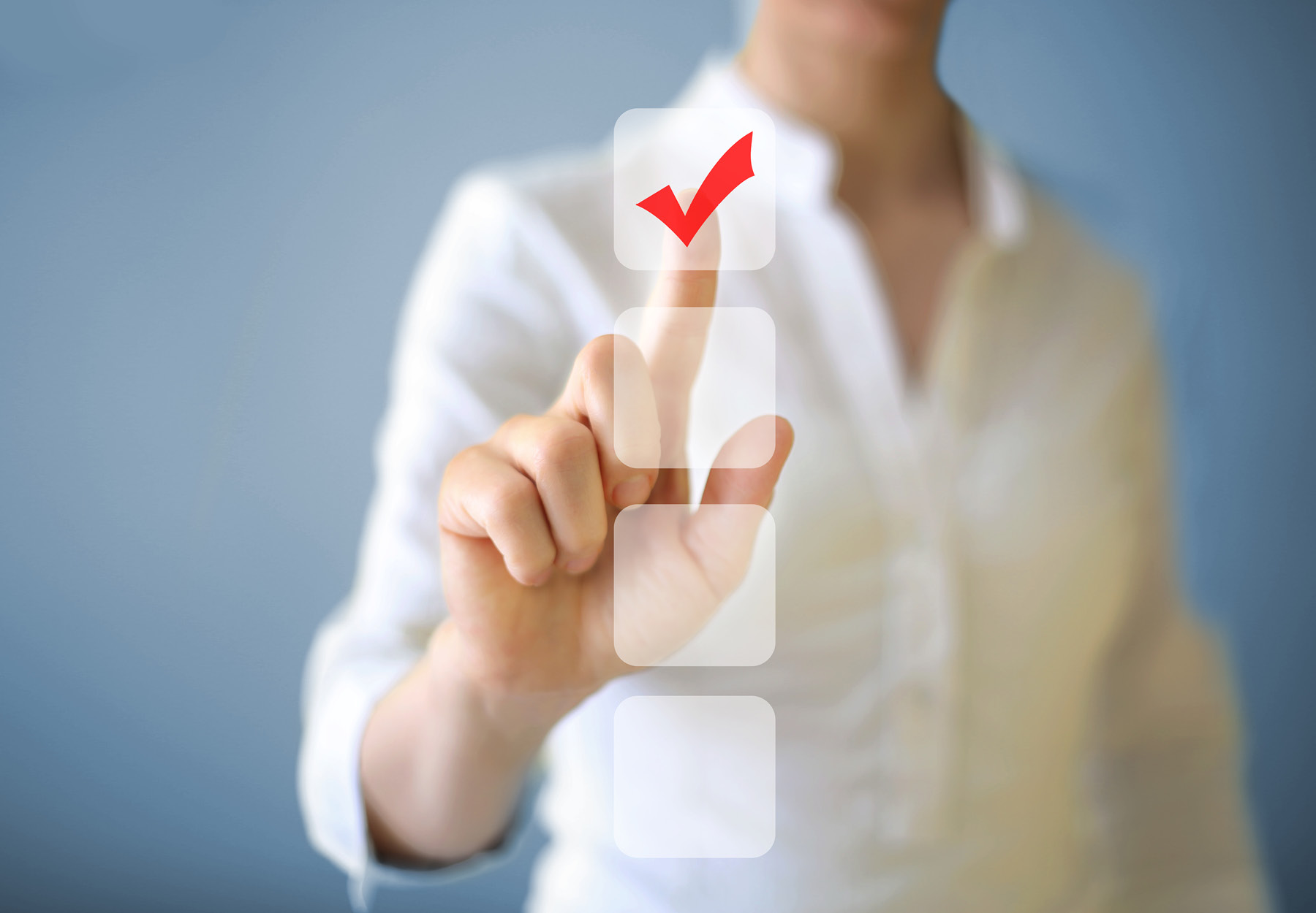 Closeup of woman pointing at a column of checkboxes. The top checkbox has a red check mark. Stock image.