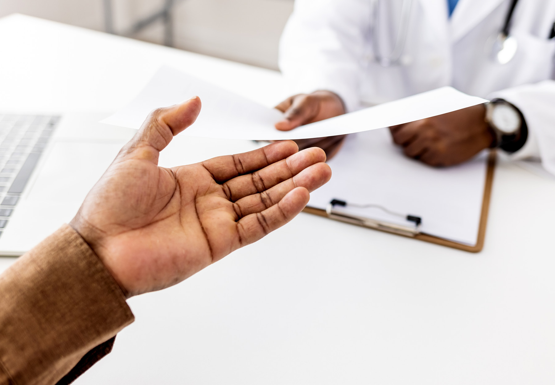 Closeup of doctor handing a form to a patient. Stock photo.