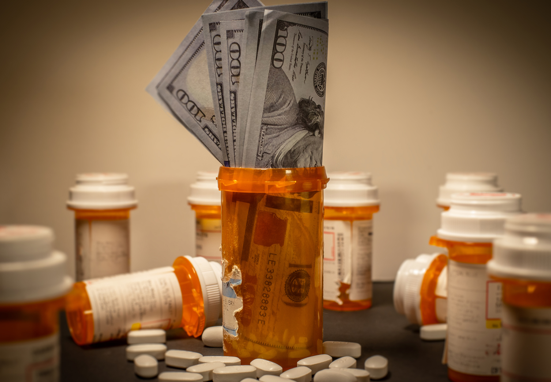 American $100 bills are stuffed into a prescription drug container. Stock photo.