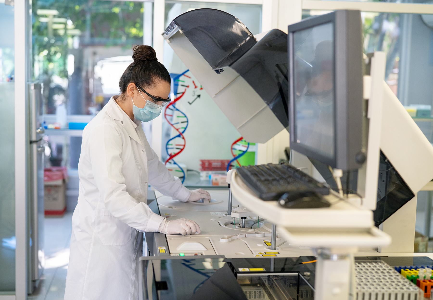 Image of white female lab employee working on a large automated machine. Stock photo.