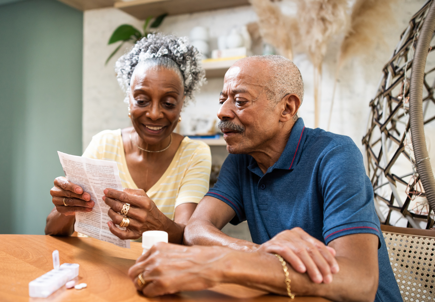 Elderly African American couple smile as they look over their Medicare paperwork. Stock photo.