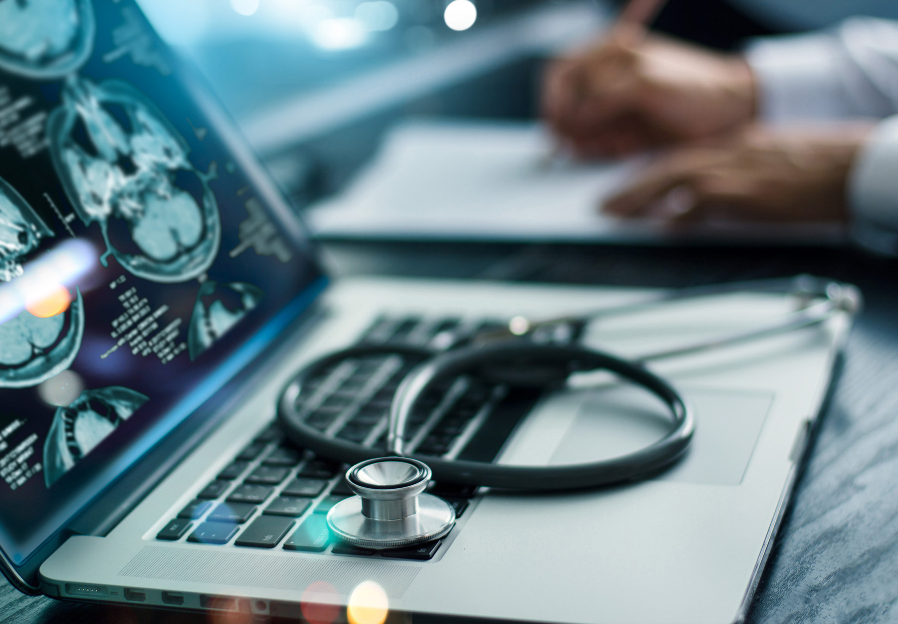 Closeup of doctor's computer monitor showing brain scans. Doctor's hands are writing notes in the background. Mental health diagnosis concept. Stock image.