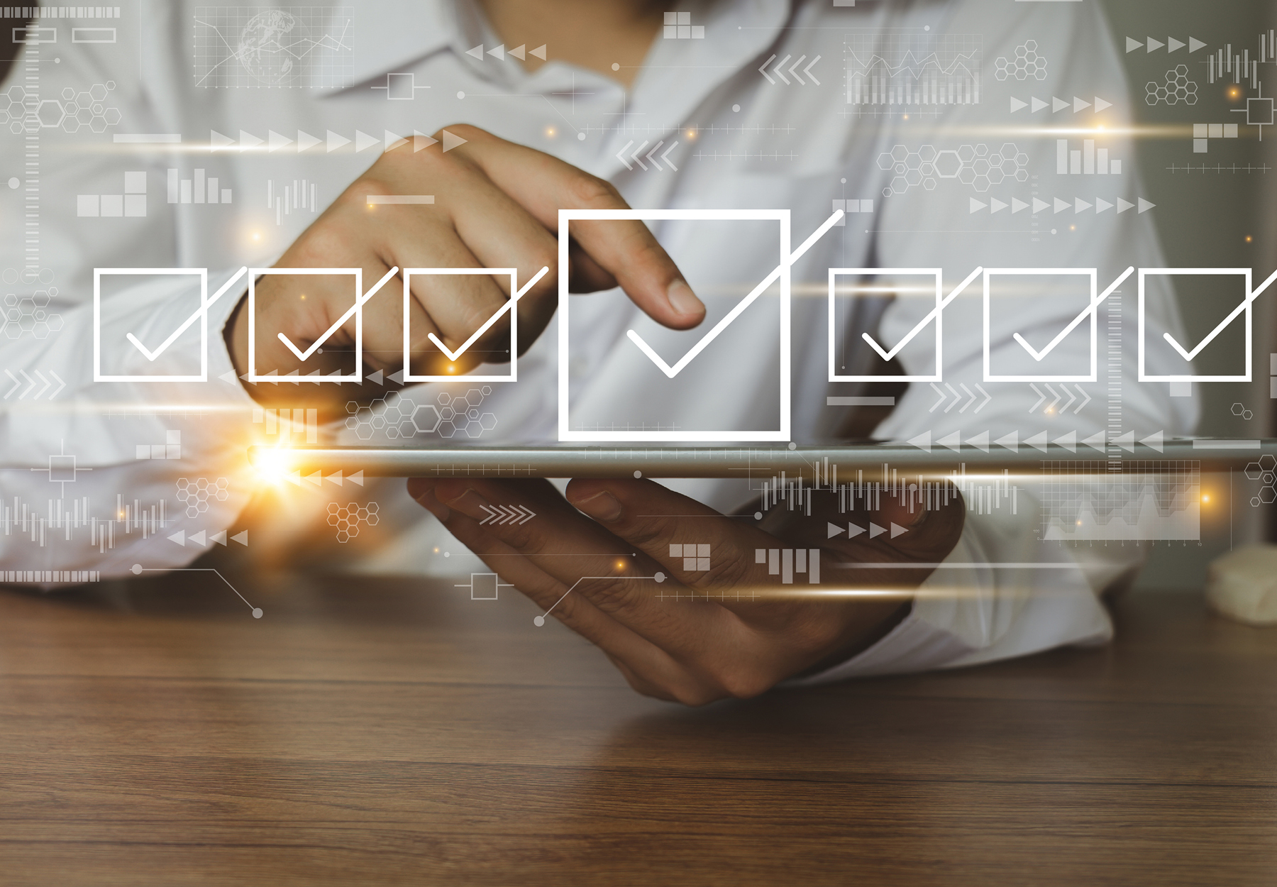 Closeup of a lab professional's hands using a tablet with checkbox graphics floating out of it to show the concept of prior authorization. iStock image.