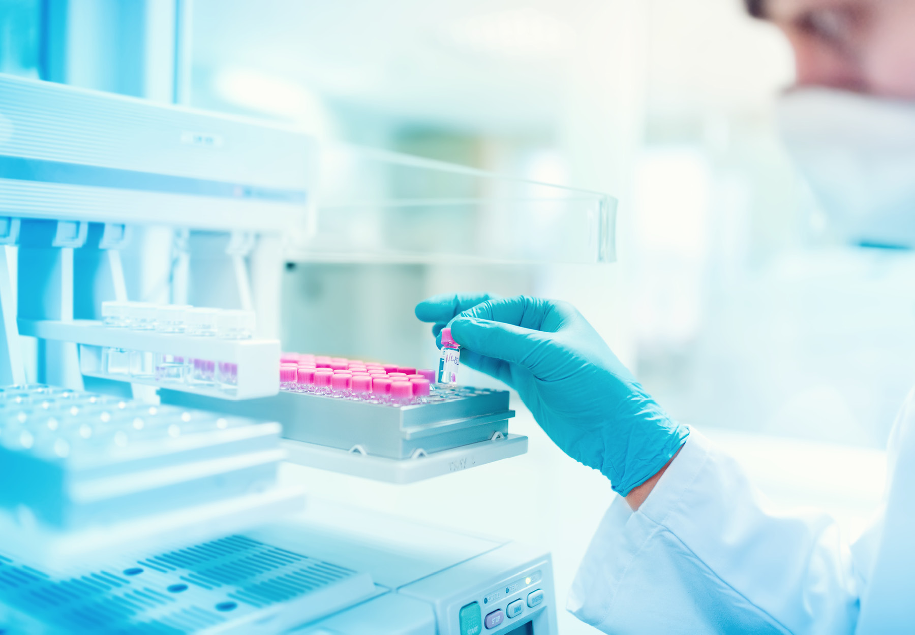 Closeup of lab professional's hand loading the sample rack of a machine. iStock image.