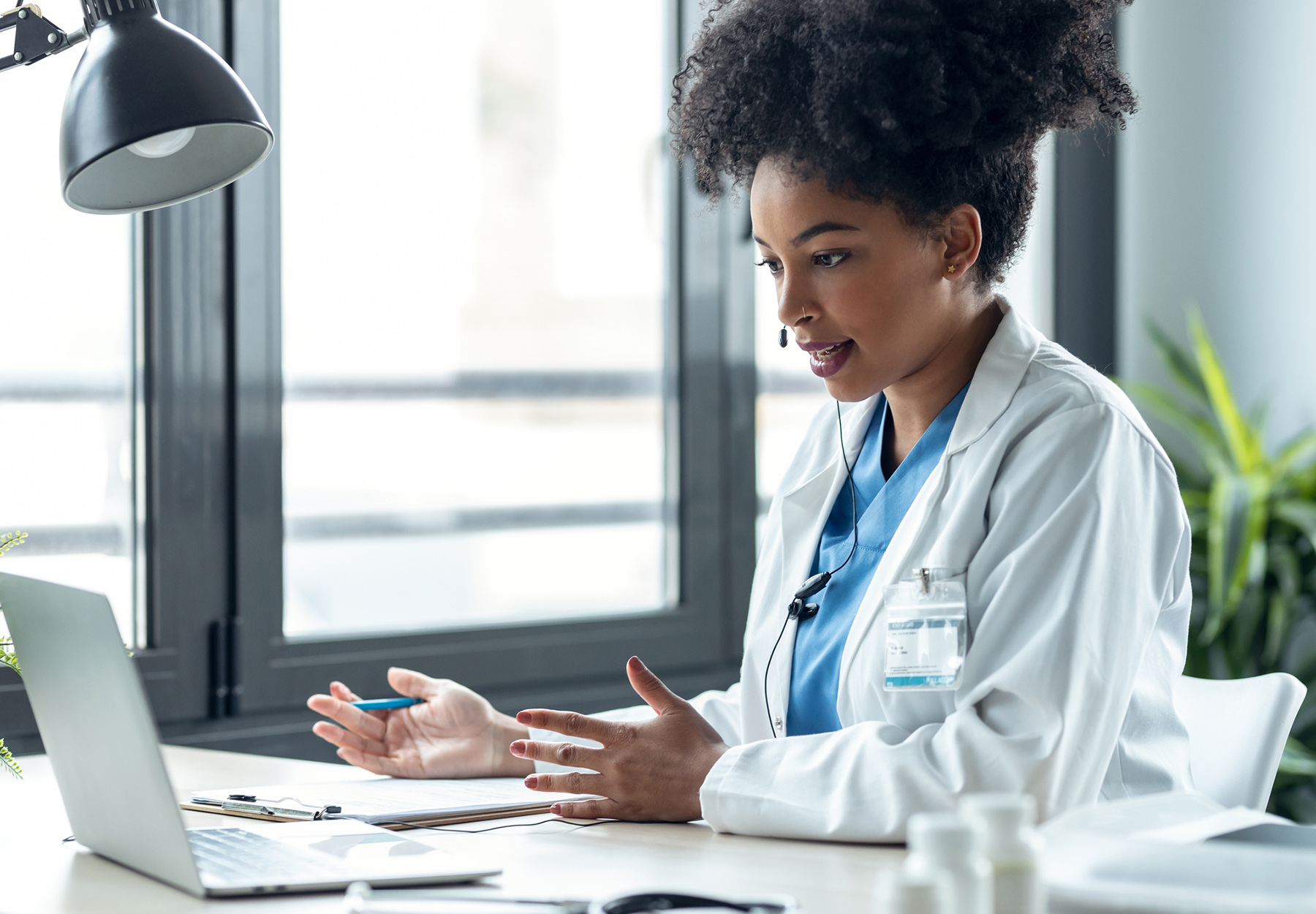 A female African American doctor with a headset is at her computer on a telemedicine call. iStock image.