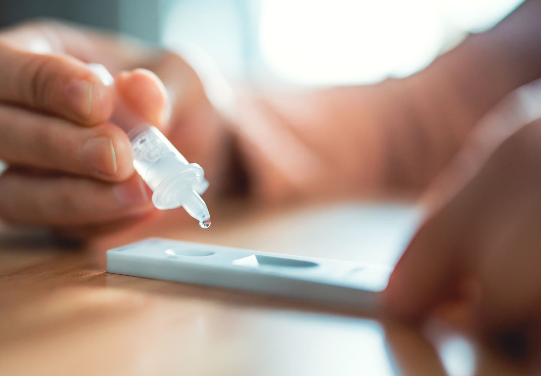 Closeup of someone using the dropper to add their sample to a COVID-29 antigen test cartridge. iStock image.