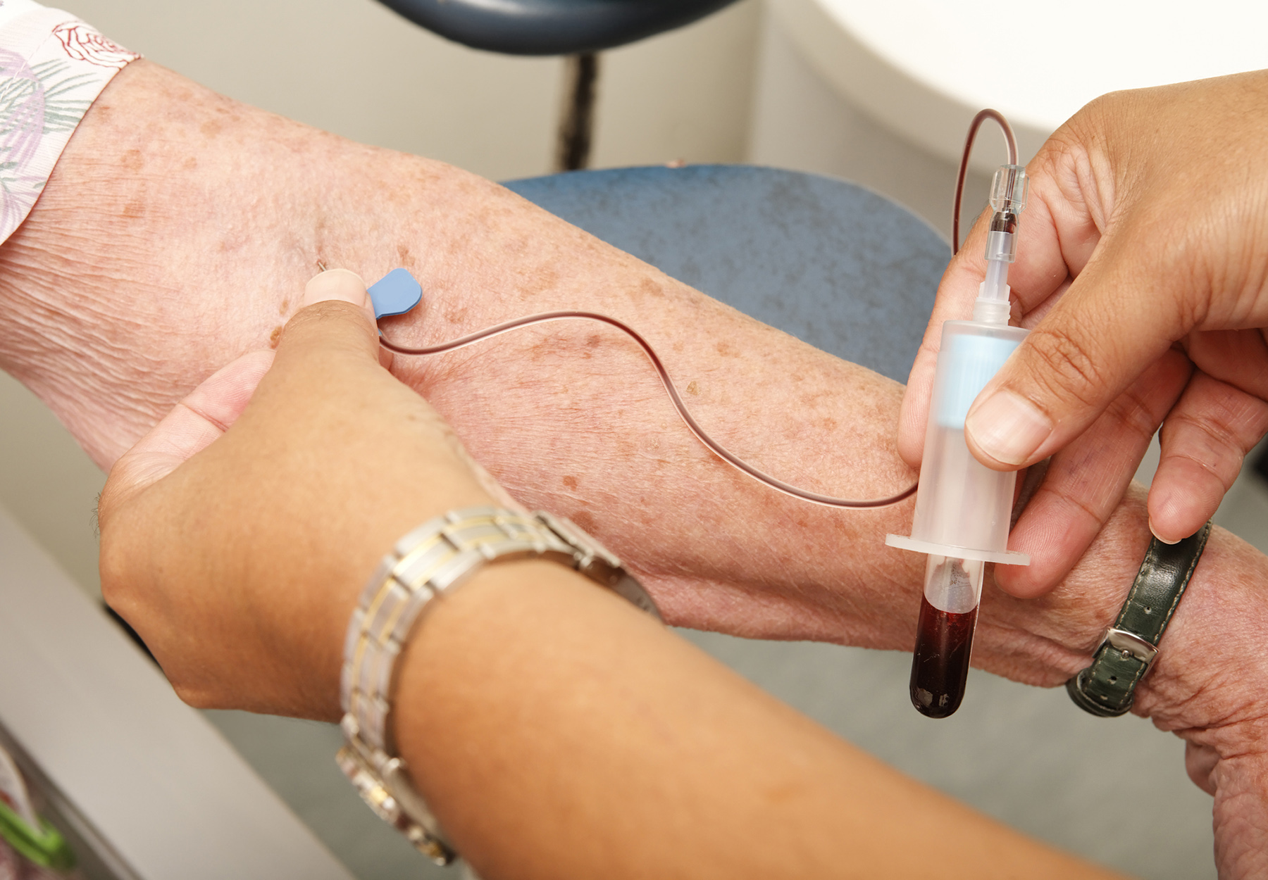 Nurse draws a vial of blood from an elderly woman for a medical test. iStock image.