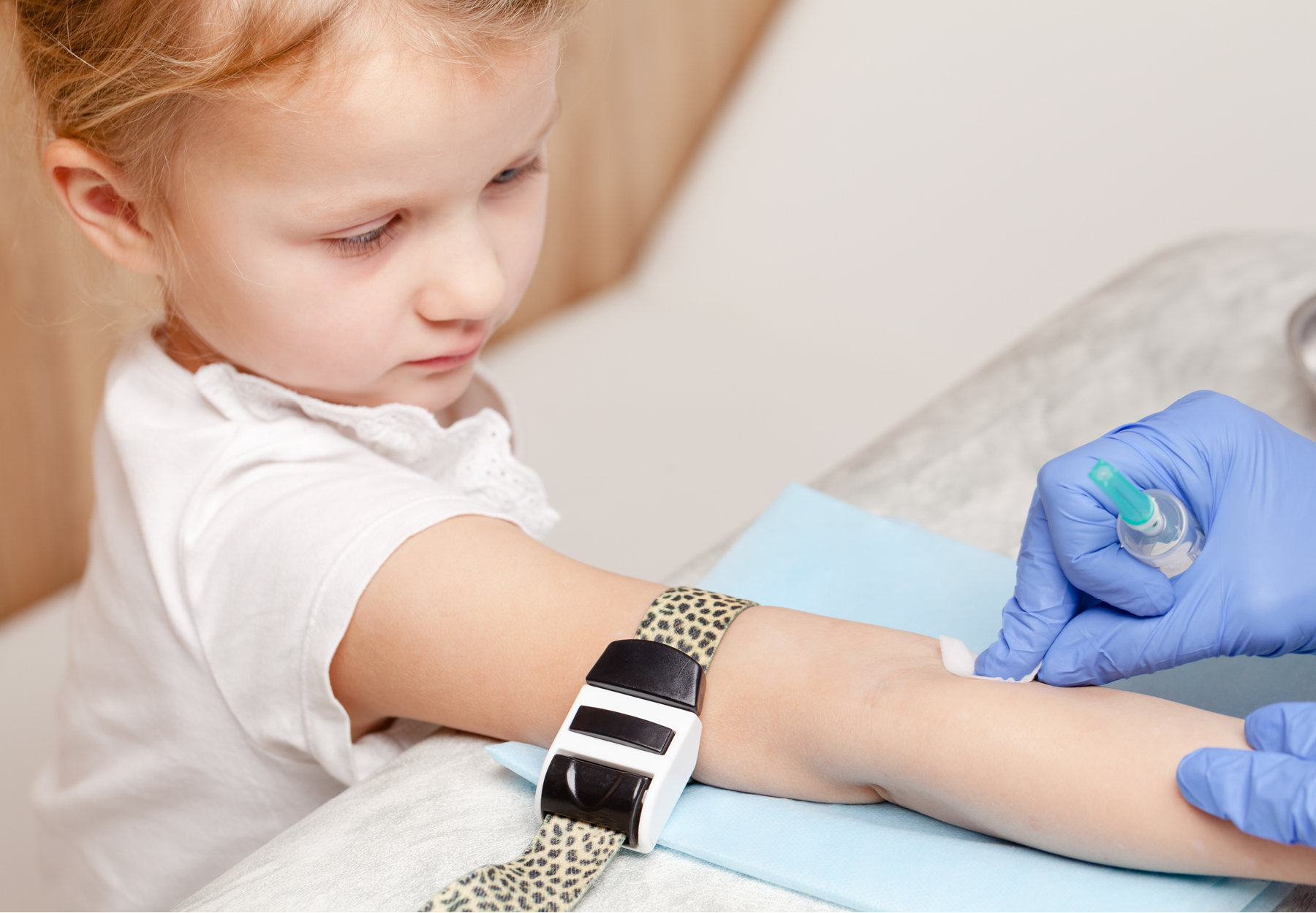 Doctor or nurse disinfecting little girl's arm preparing to take a blood sample from her vein. Pediatric venipuncture or venepuncture procedure. iStock image.